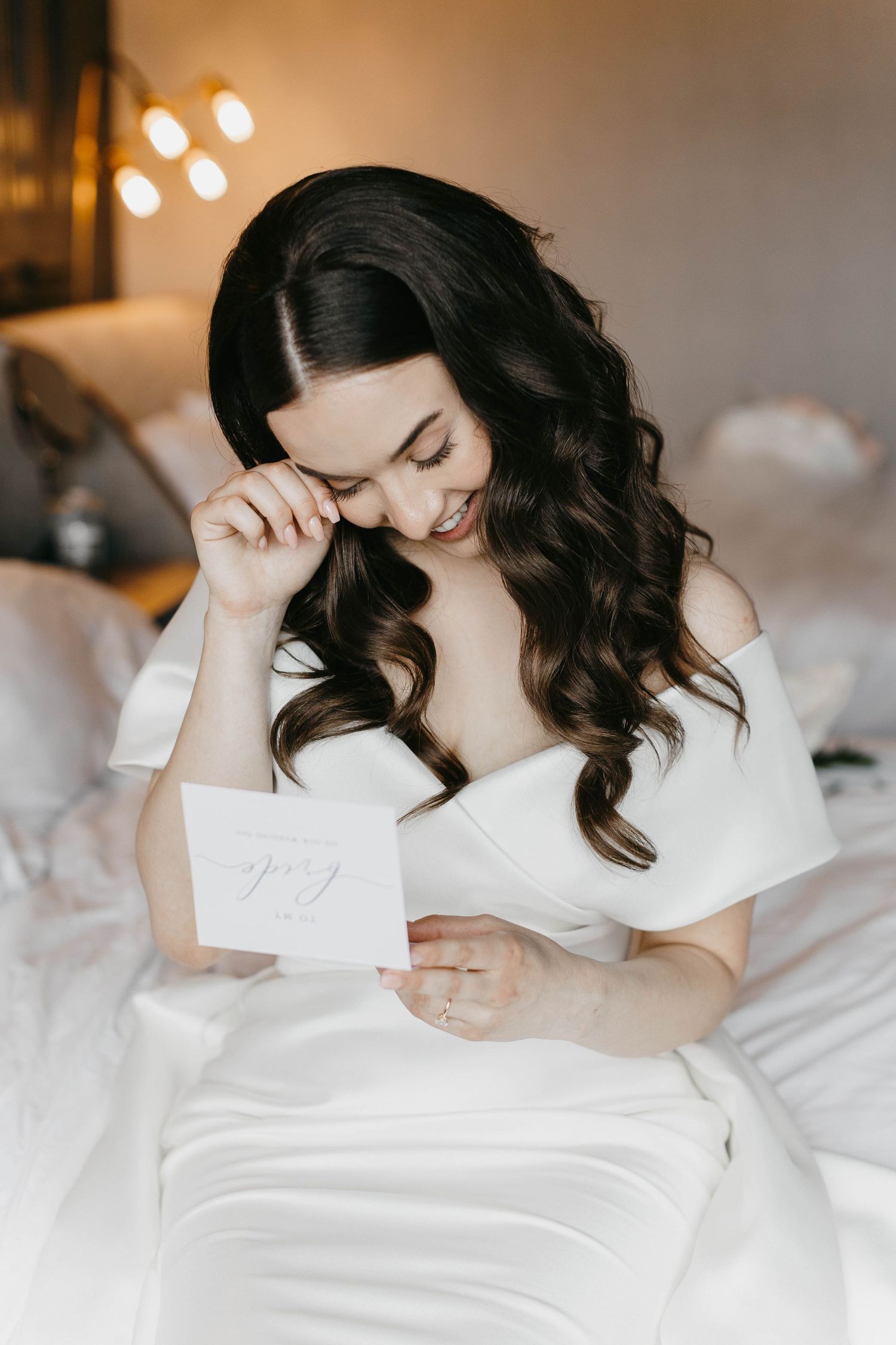 A quiet moment reading a letter while sitting in white bedding.
