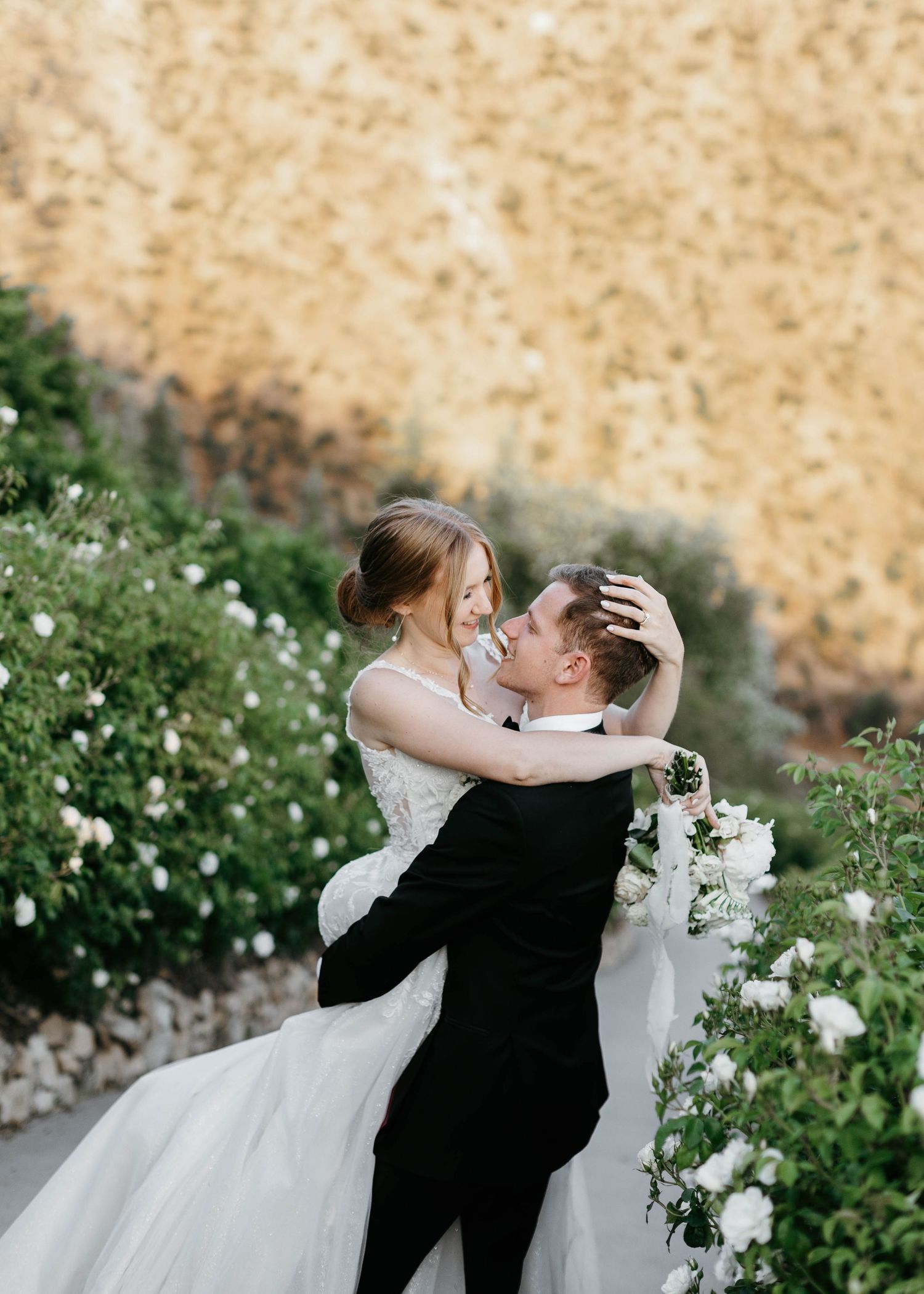 Newlyweds sharing a romantic moment among blooming white flowers.