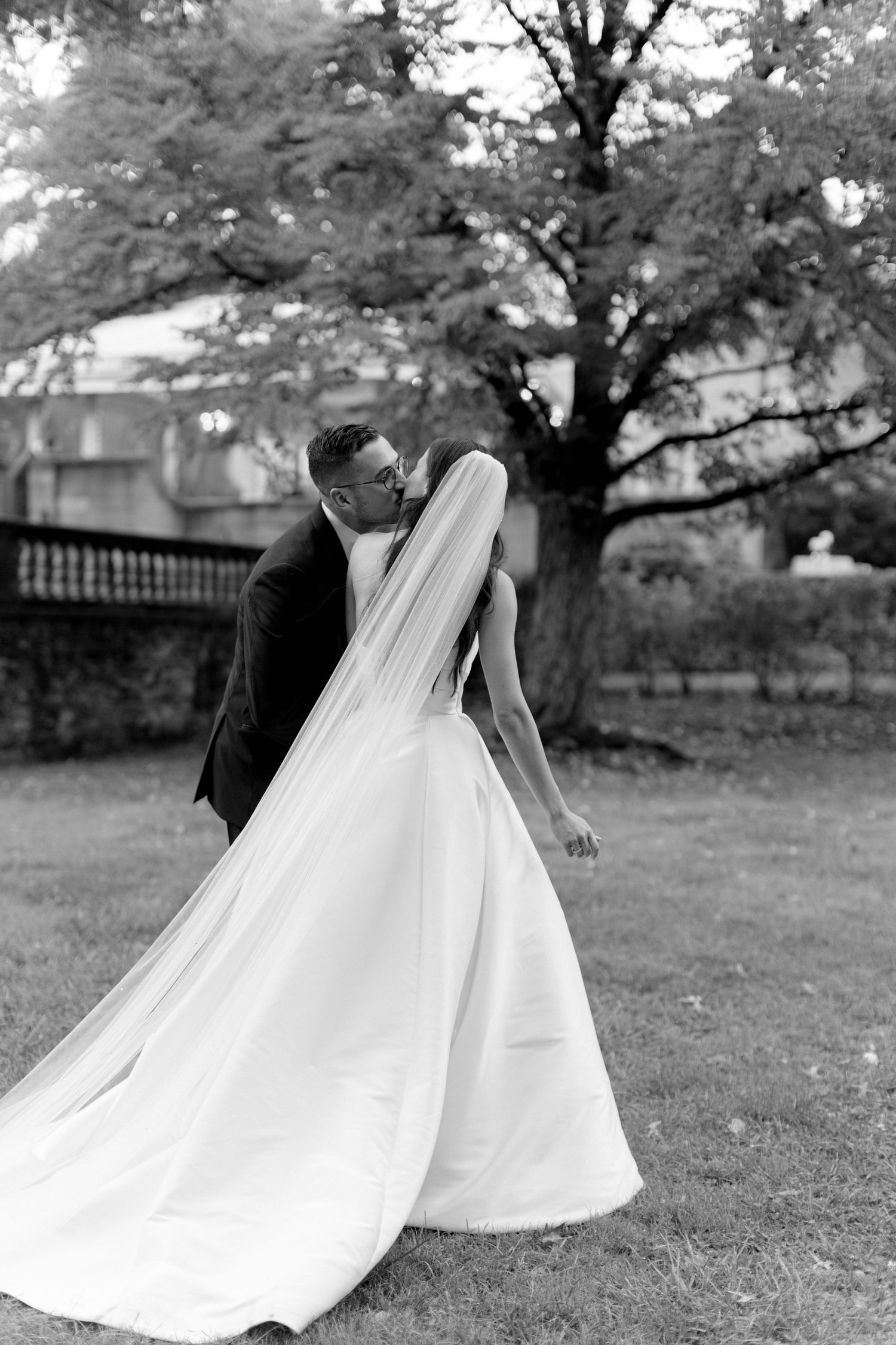Black and white photo of wedding couple walking through a garden setting.