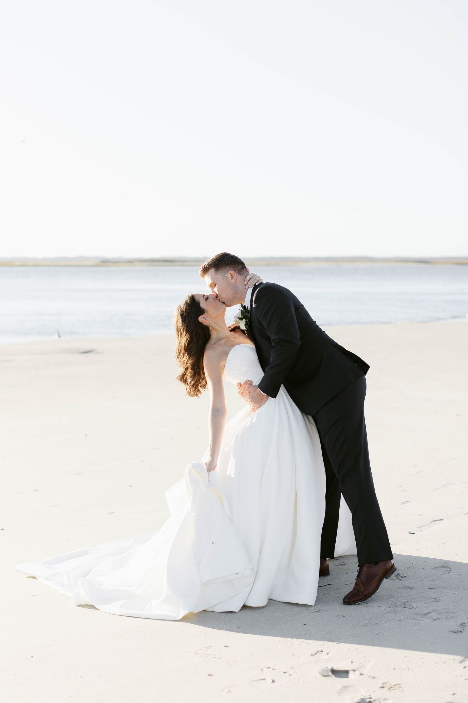 Romantic beach wedding photos capture playful moments between newlyweds on sandy shore.