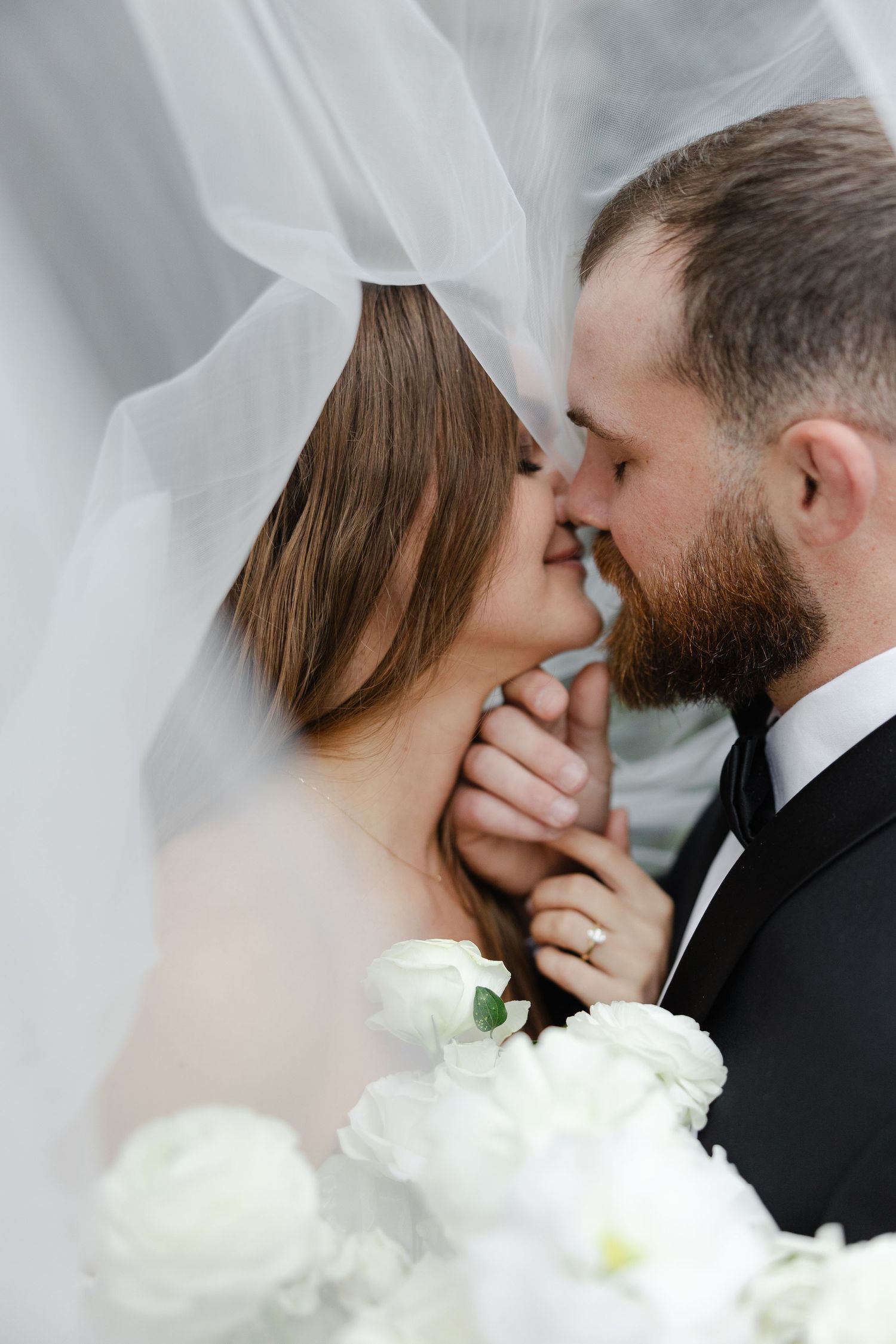 Romantic wedding moment with white bouquet and flowing veil.