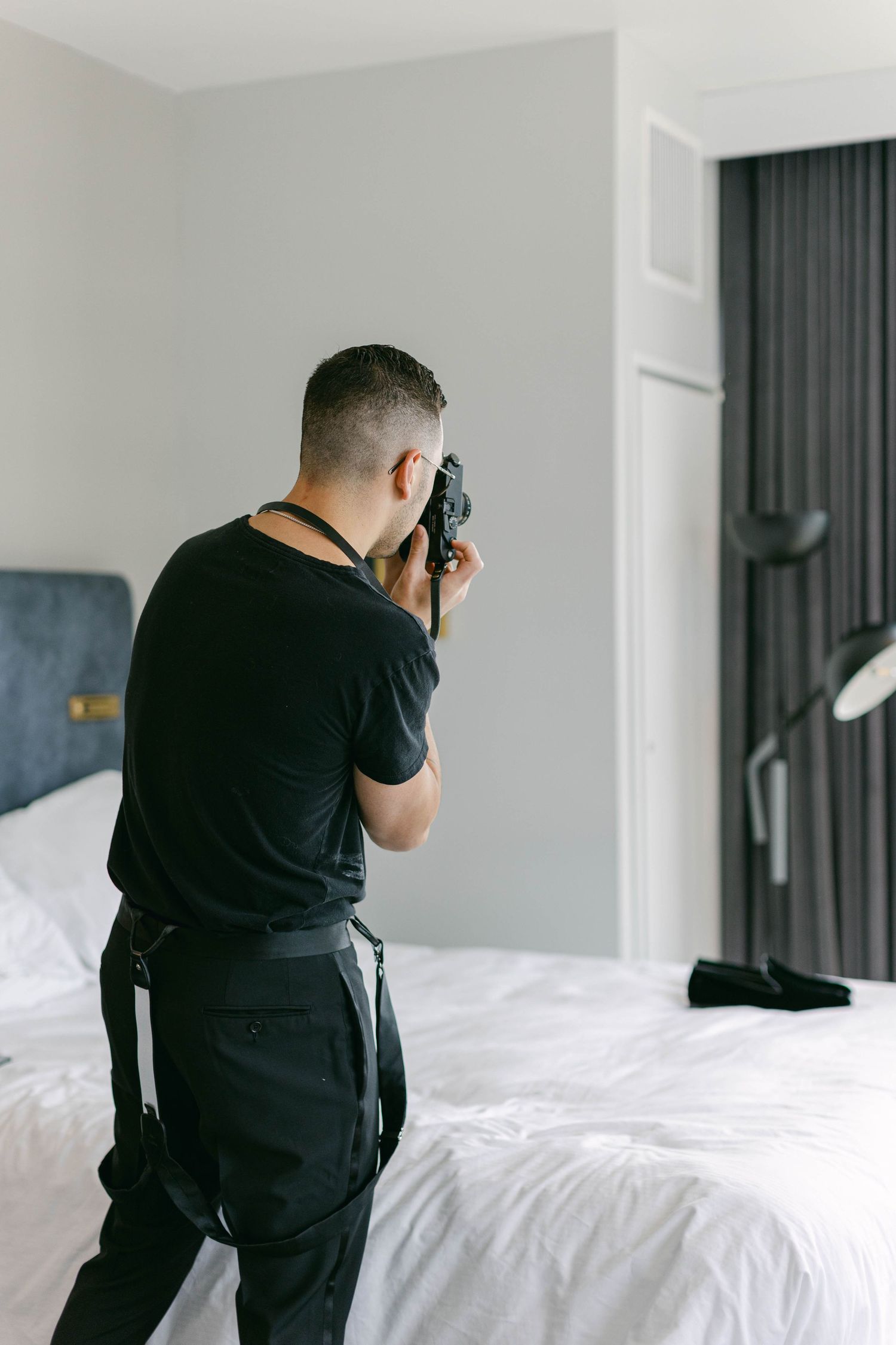 Professional photographer in black capturing shots in a bright hotel room.