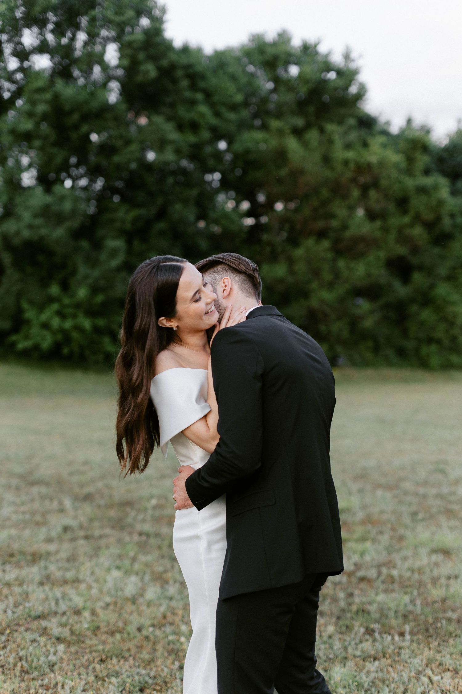 Romantic outdoor wedding portraits in a serene field with classic formal attire.