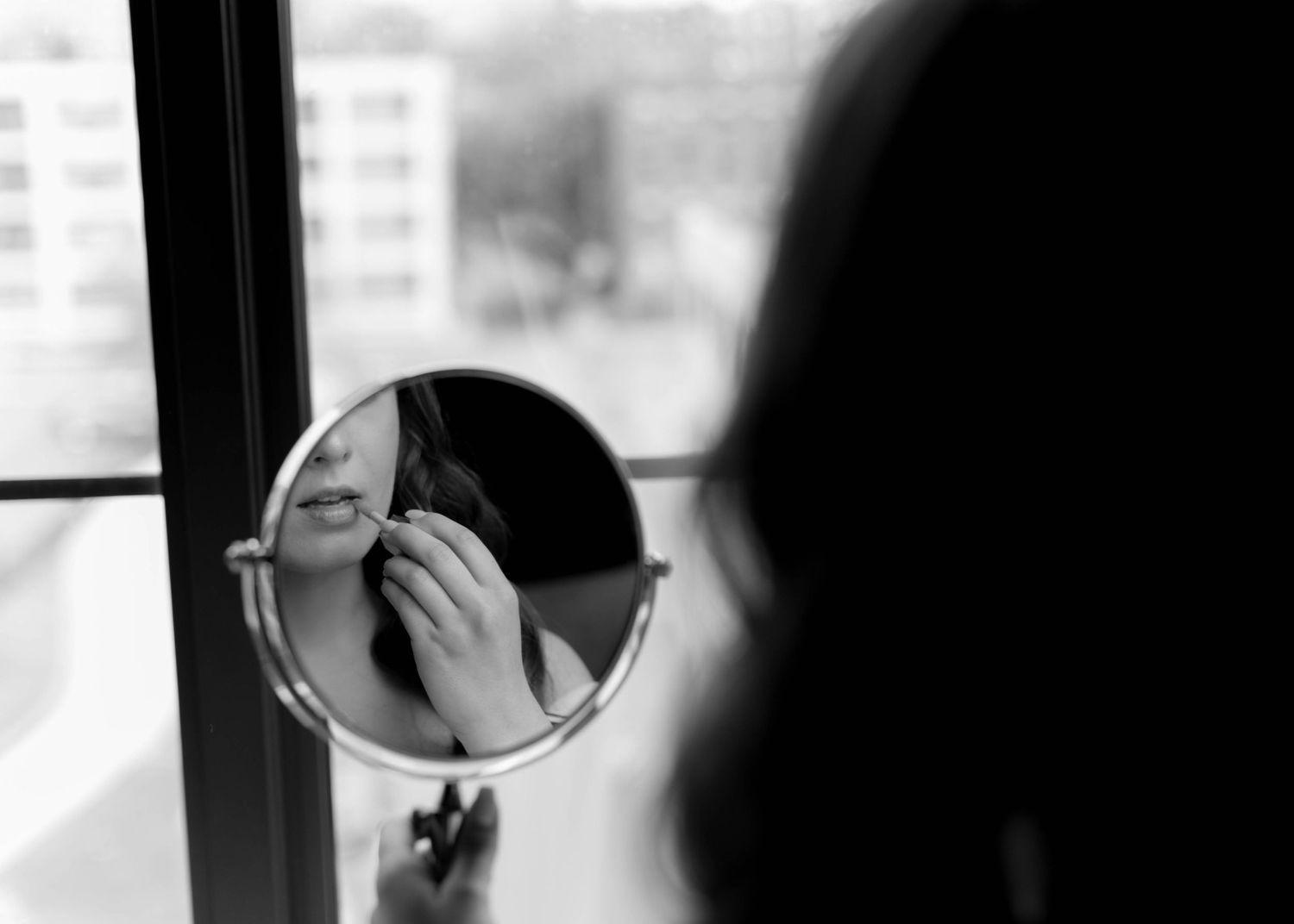 Black and white image of someone getting ready in front of a mirror.