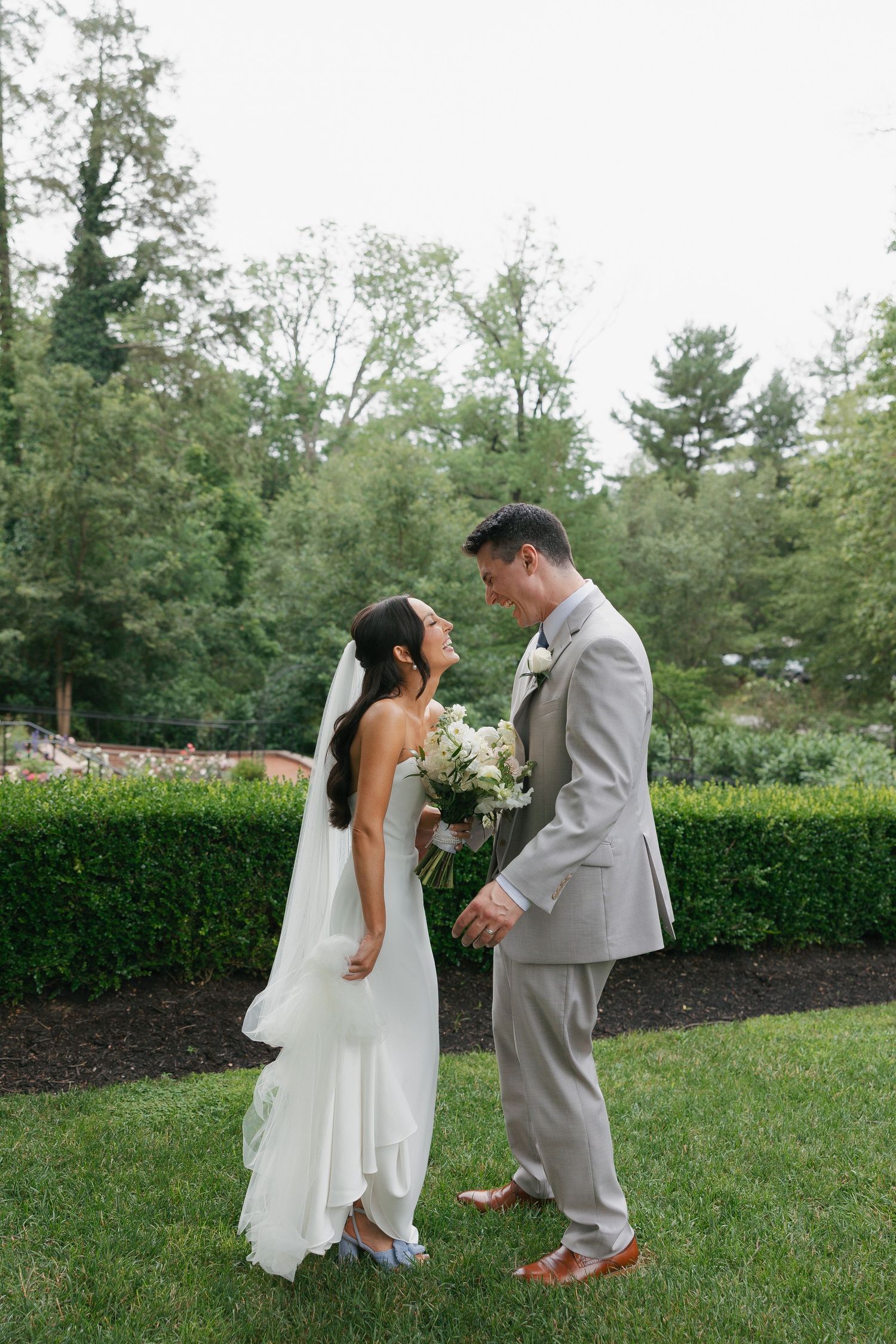 A bride and groom share a romantic moment in a garden during cocktail hour with lush greenery and flowers in the background philly photo