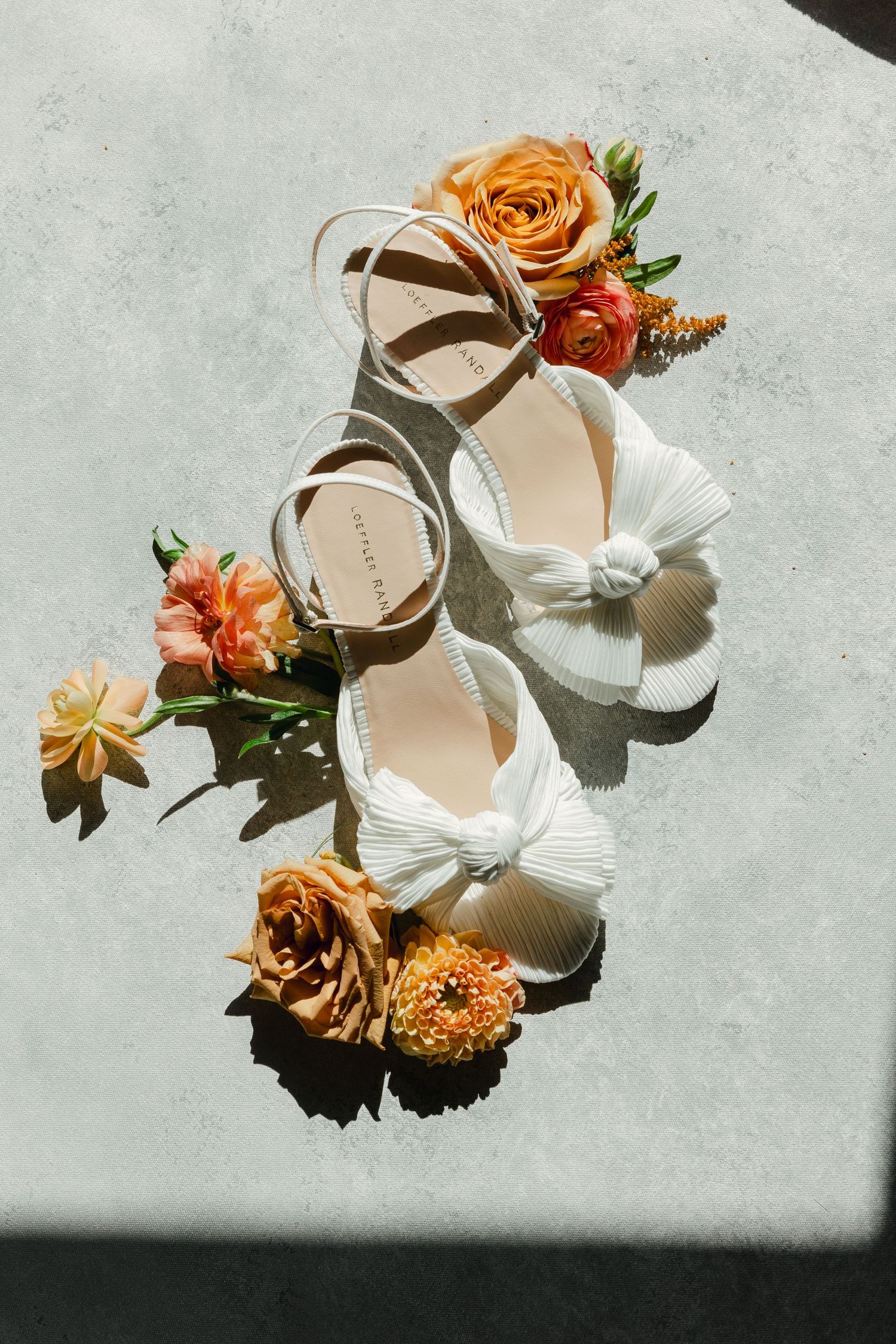 Elegant Loeffler Randalls wedding sandals adorned with delicate peach and orange roses against a light textured background. wedding details