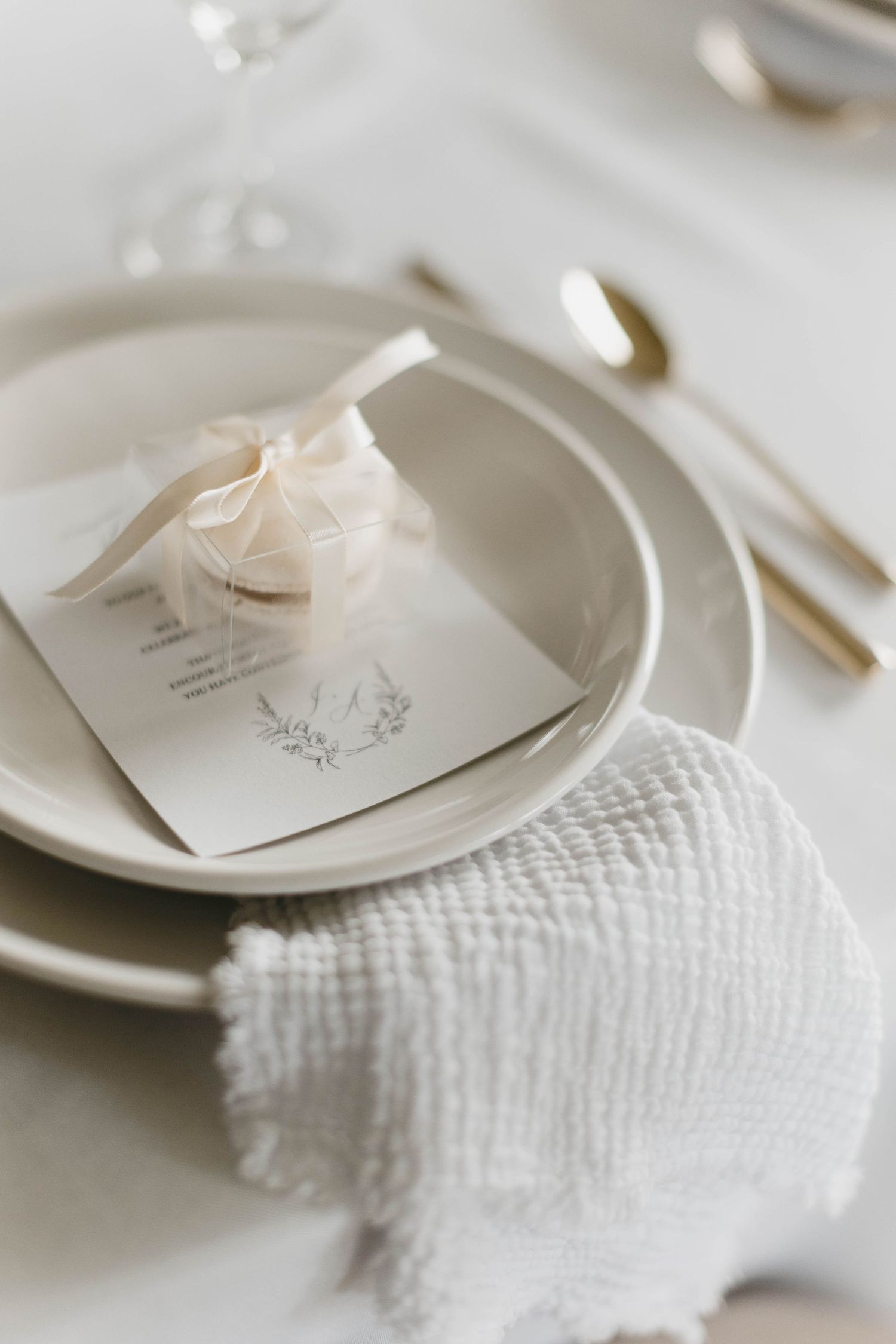Minimalist place setting with white textured napkin and elegant stationery on cream plates.