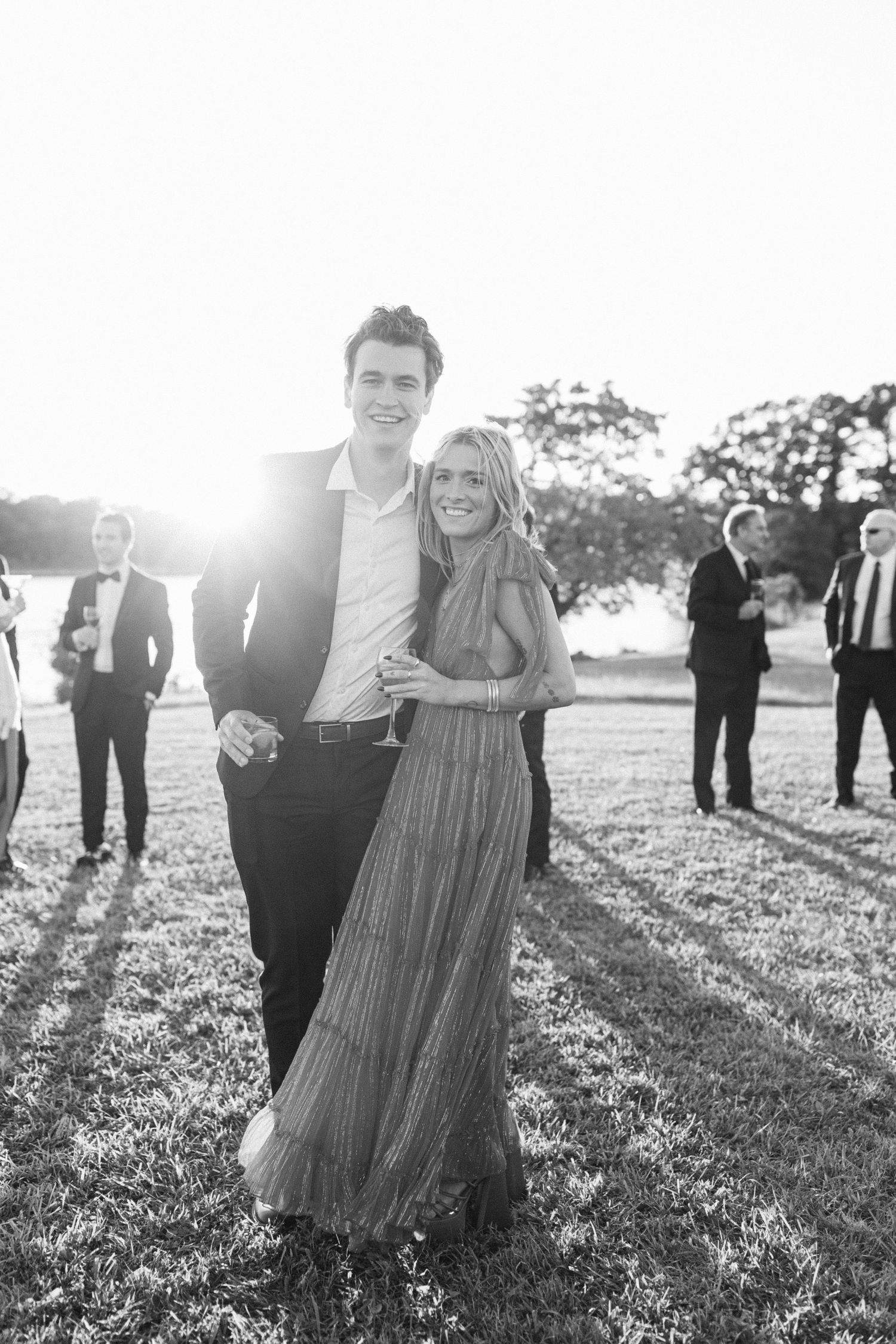 Joyful couple dancing and twirling in a sunlit field during golden hour.