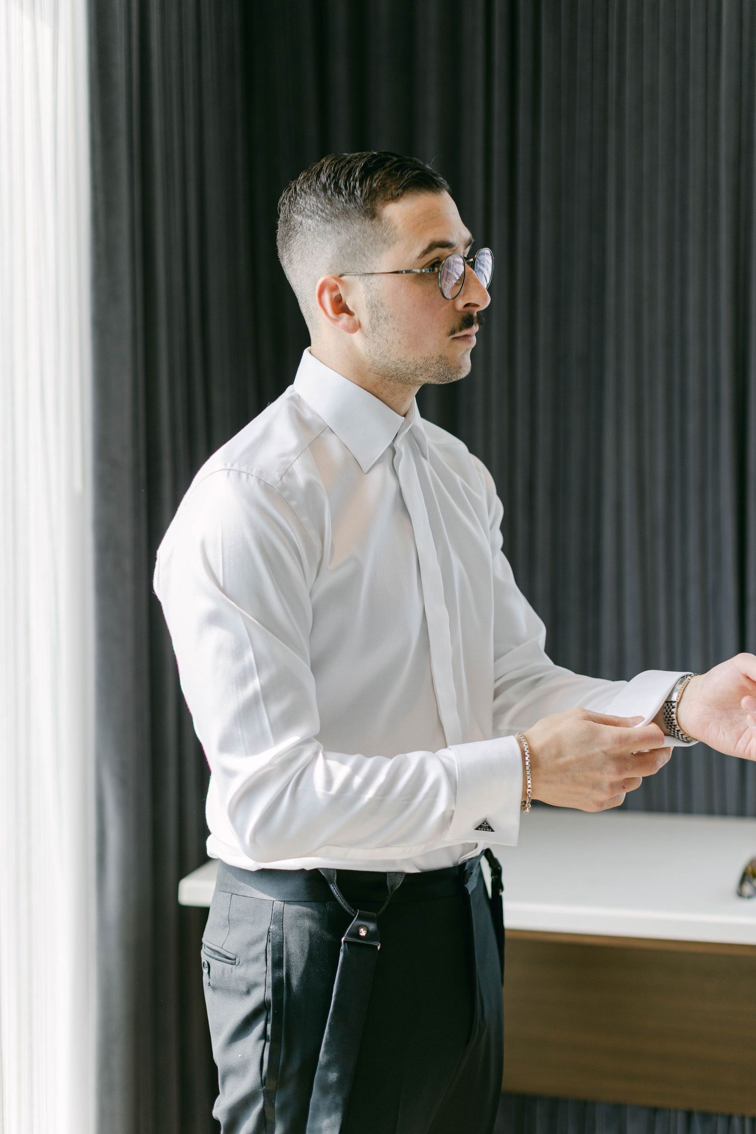 Man in white dress shirt leaning over a table in a modern indoor setting.