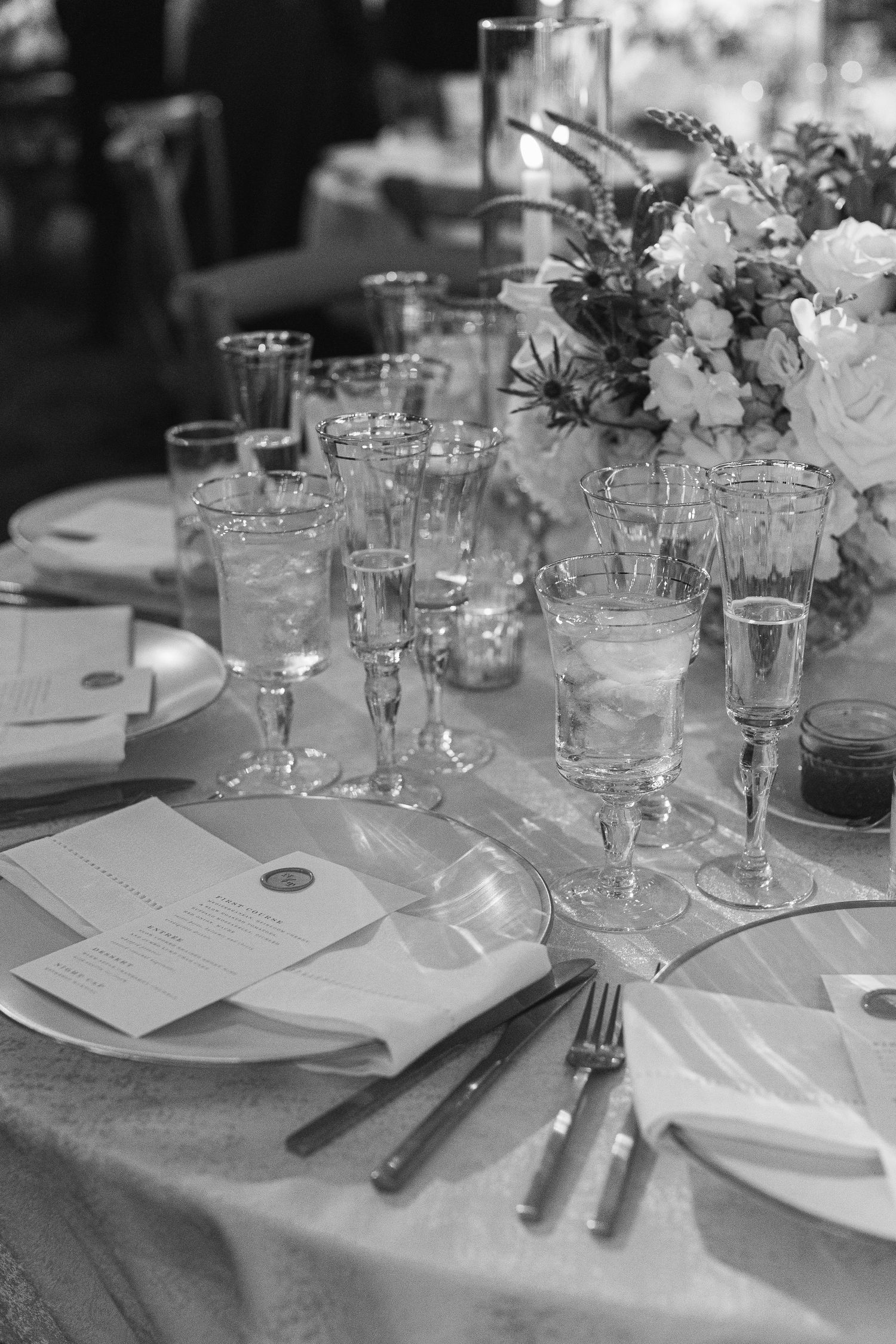 Black and white photo of formal wedding reception table with glassware and place settings.