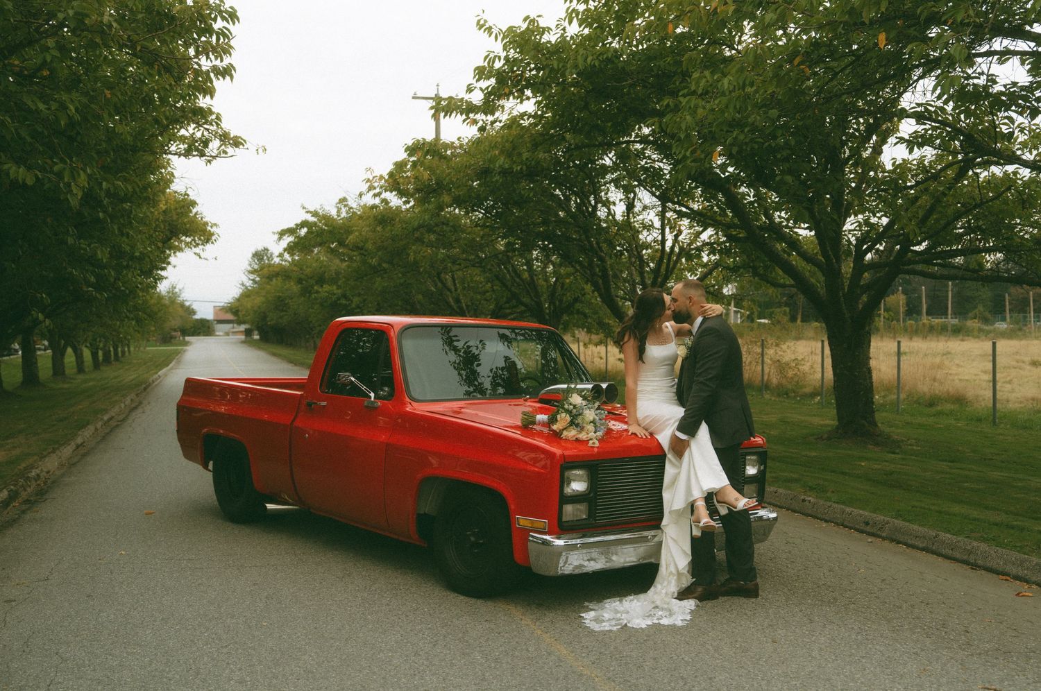 Series of wedding photos with a bright red classic car on a tree-lined pathway.