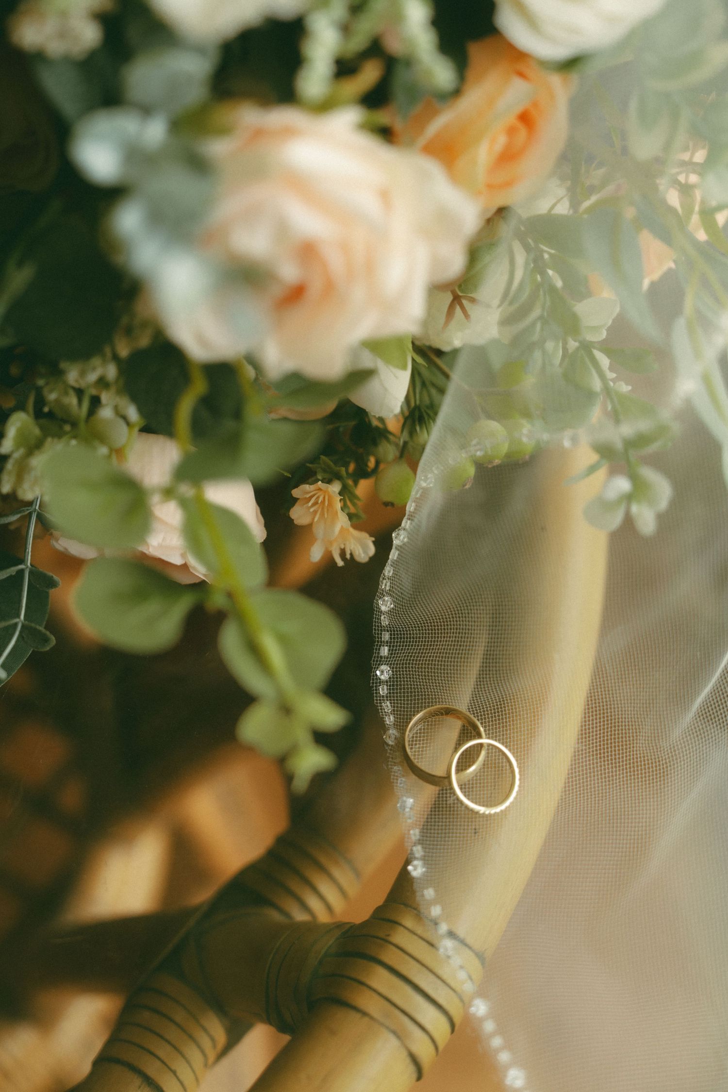 Close-up detail of white and peach roses with cascading greenery and ribbon accents.