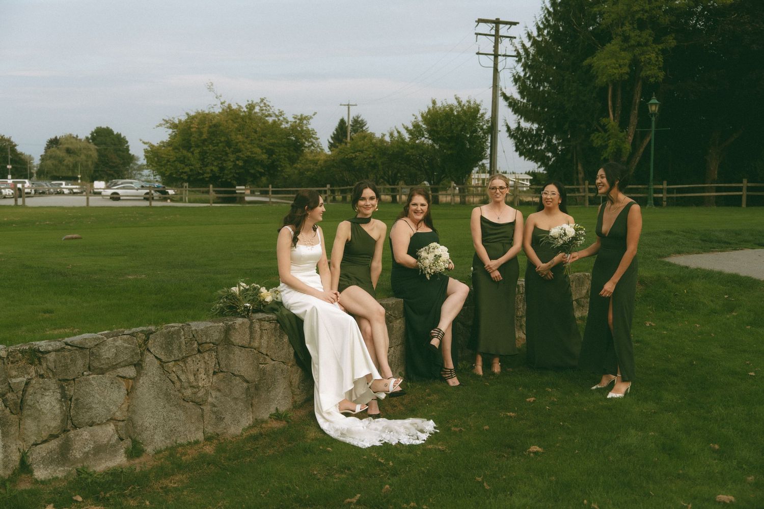 Wedding party poses on stone wall during outdoor photo session.