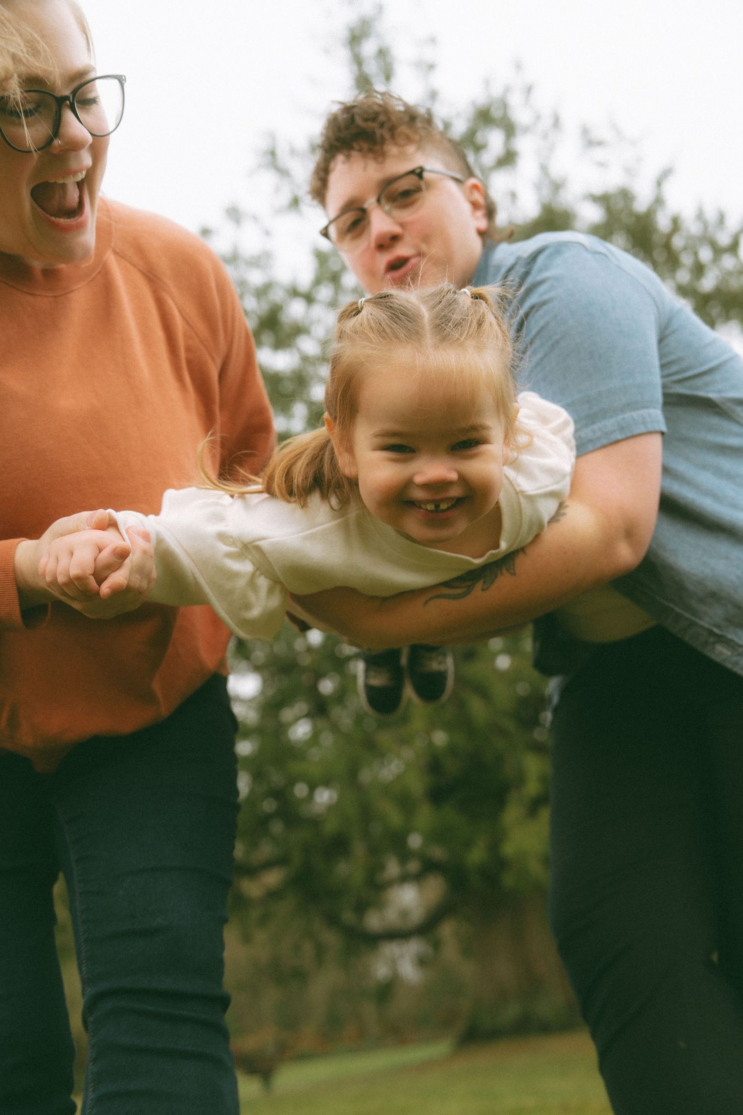 Playful family moment captured in motion against a green outdoor background.