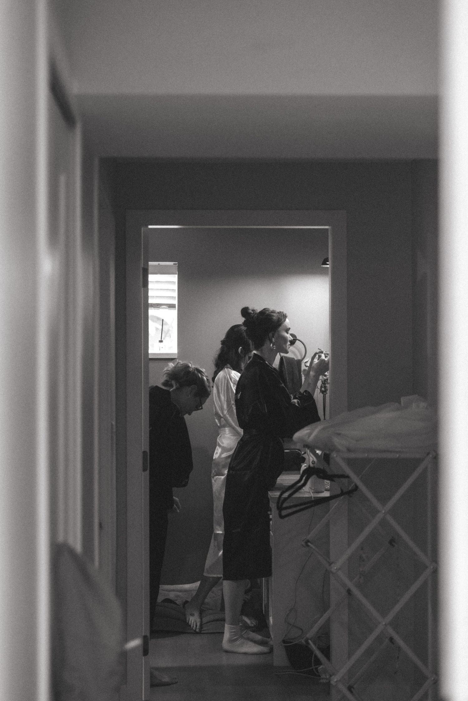 Behind-the-scenes black and white photo of wedding preparations in a hallway.