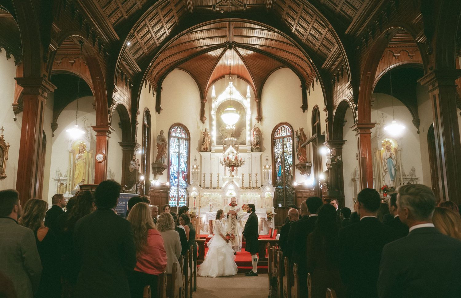 Wedding ceremony in historic church with vaulted ceilings and stained glass windows.