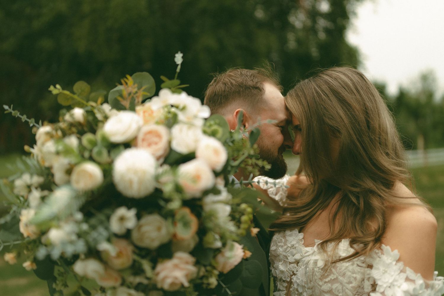 Delicate peach and cream roses arranged in an elegant wedding bouquet with soft greenery.
