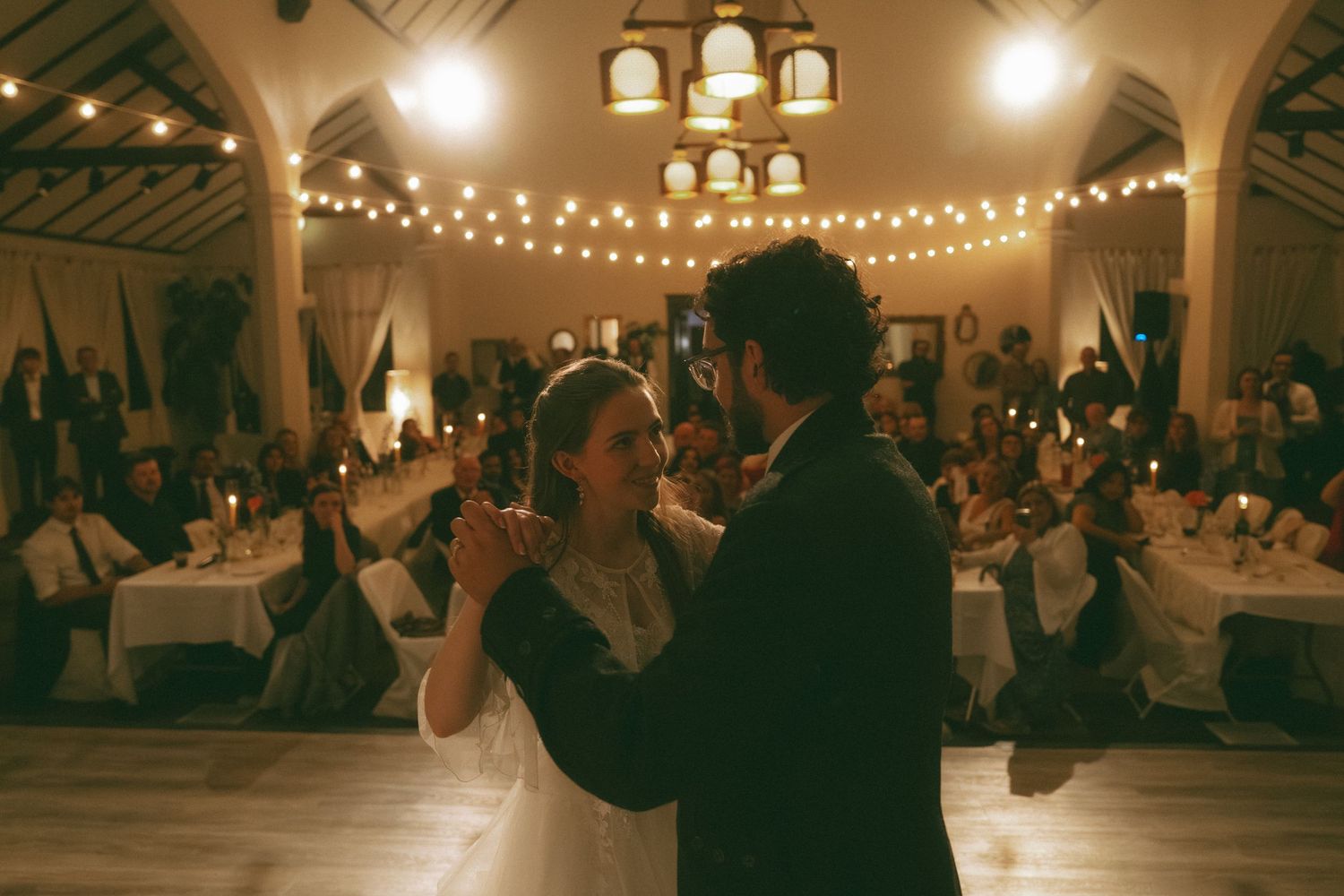 Dance floor at wedding reception with string lights creating warm ambient atmosphere.