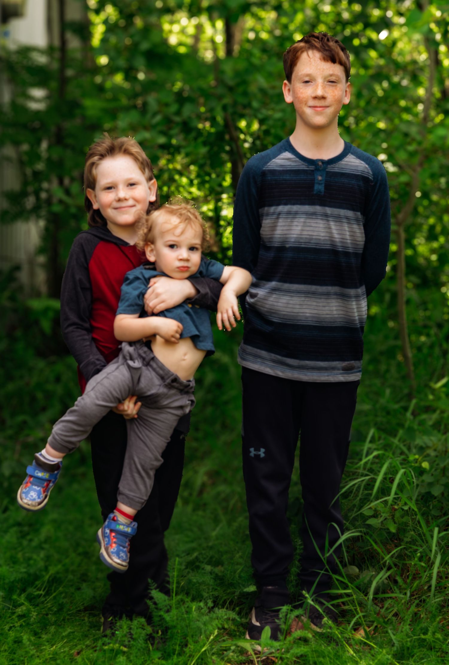 Children playing and being carried in a wooded outdoor area.