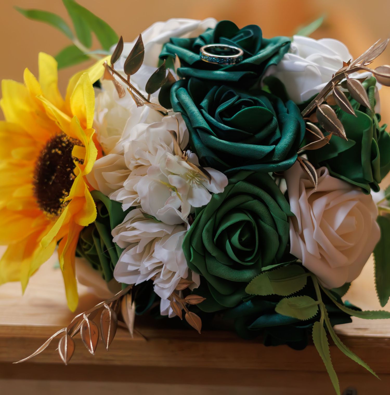 Wedding floral arrangement featuring teal roses, white flowers, and bright yellow sunflowers.