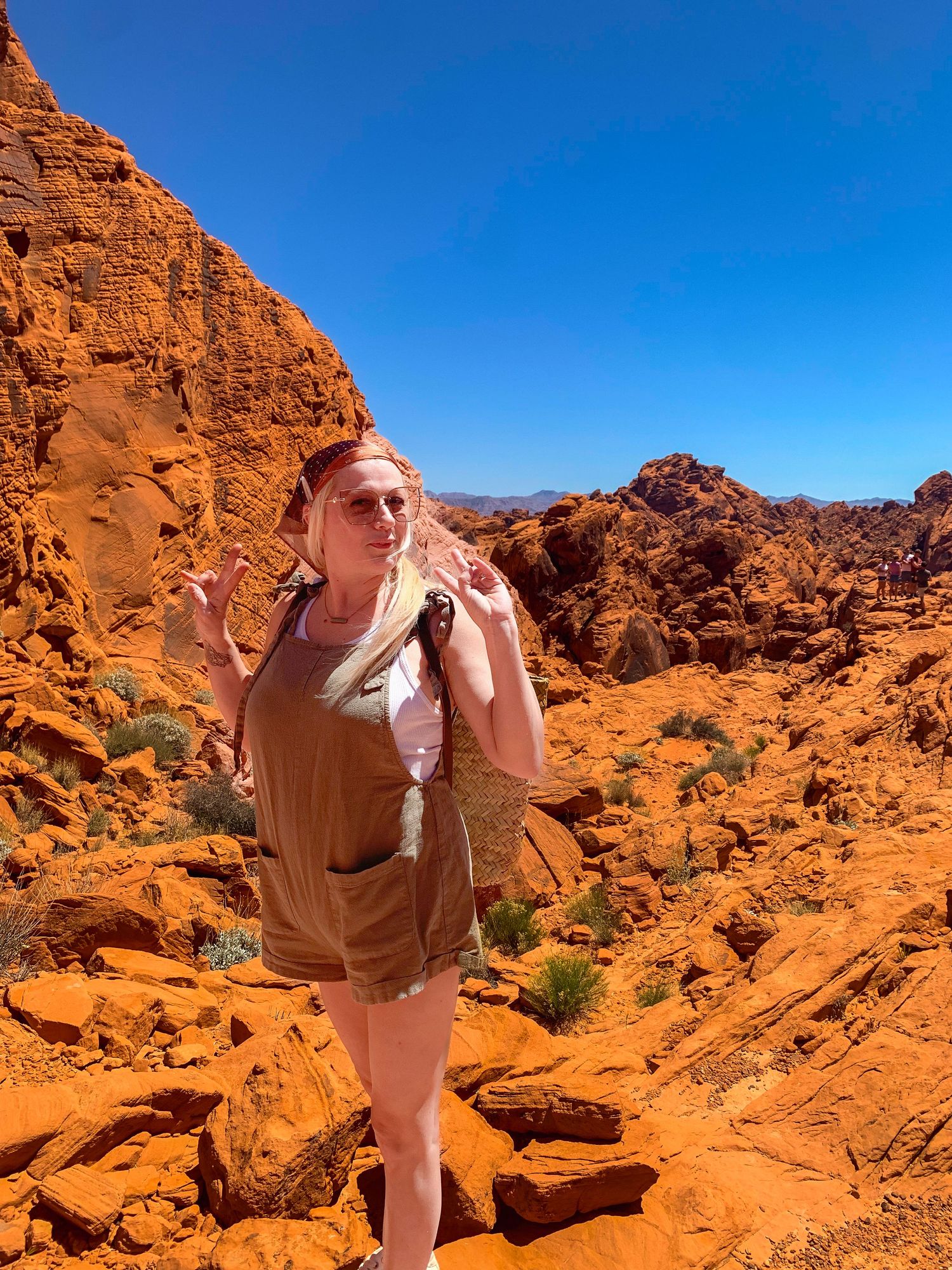 Hiker exploring red sandstone formations in Valley of Fire State Park under clear blue skies.