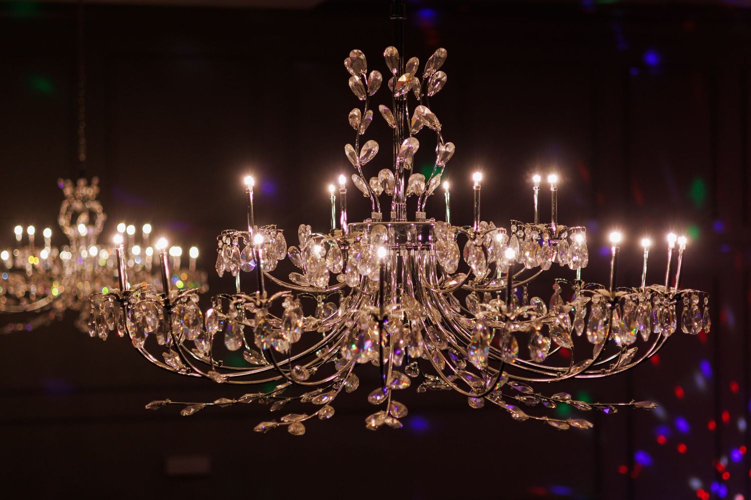 Crystal chandeliers illuminated in a dark room creating a dramatic lighting effect.