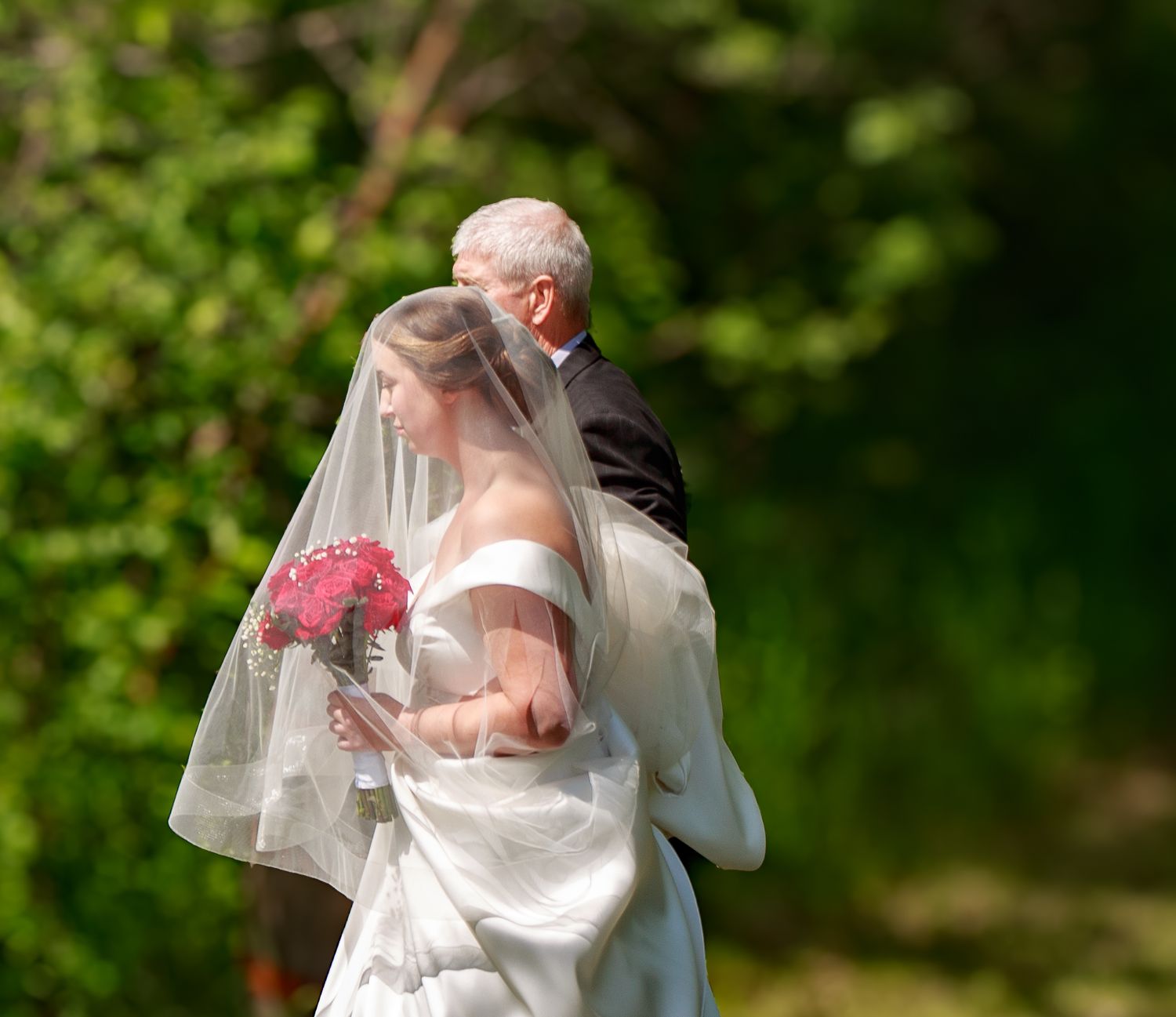 Wedding party celebrates outdoors against a backdrop of vibrant green foliage.