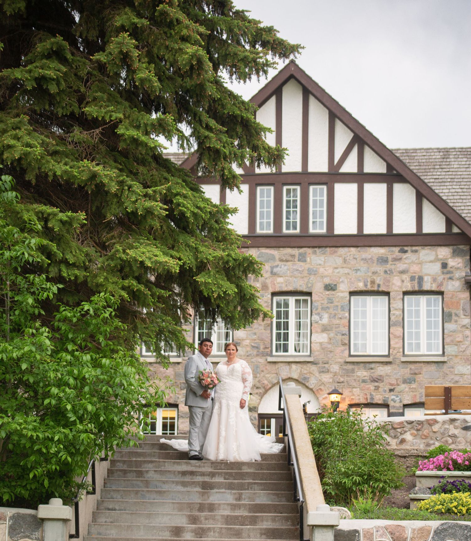 Stone mansion with Tudor architectural details features grand staircase and landscaped gardens.