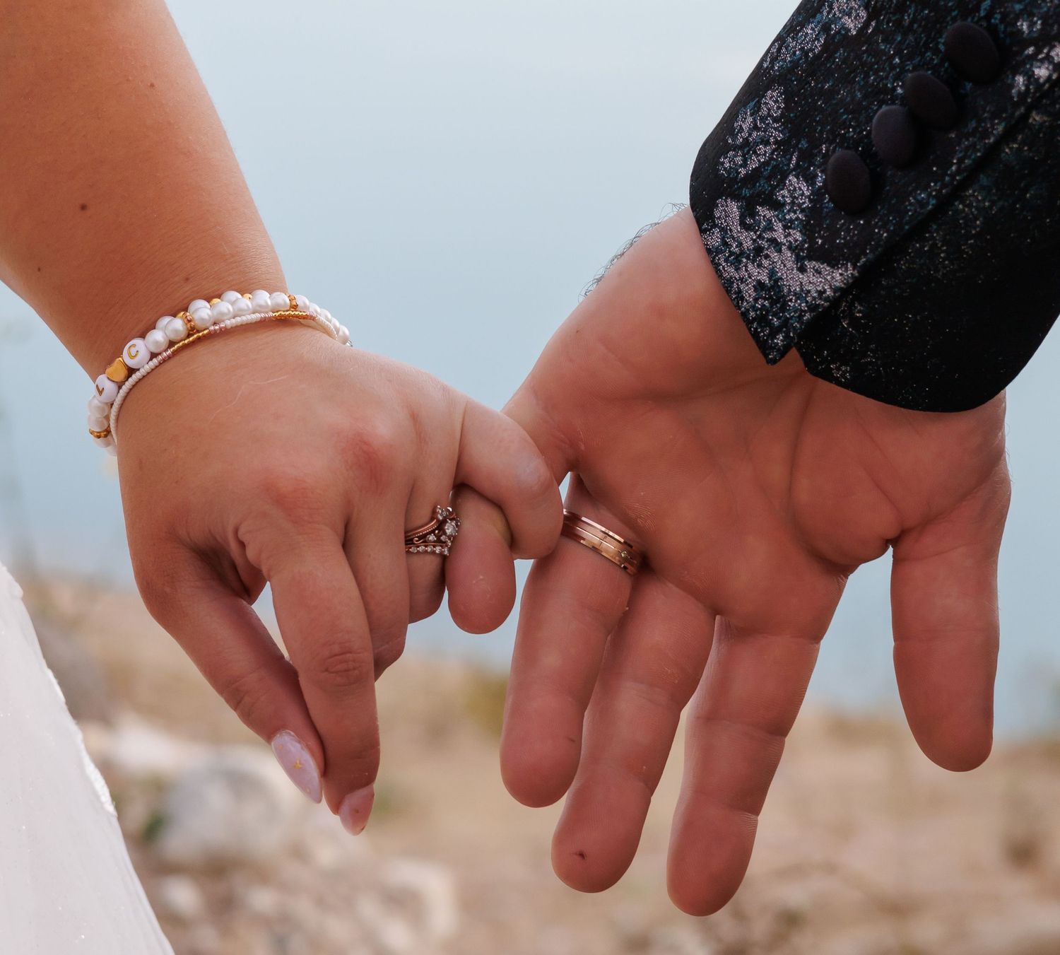 Close-up of hands displaying wedding rings against a light background.