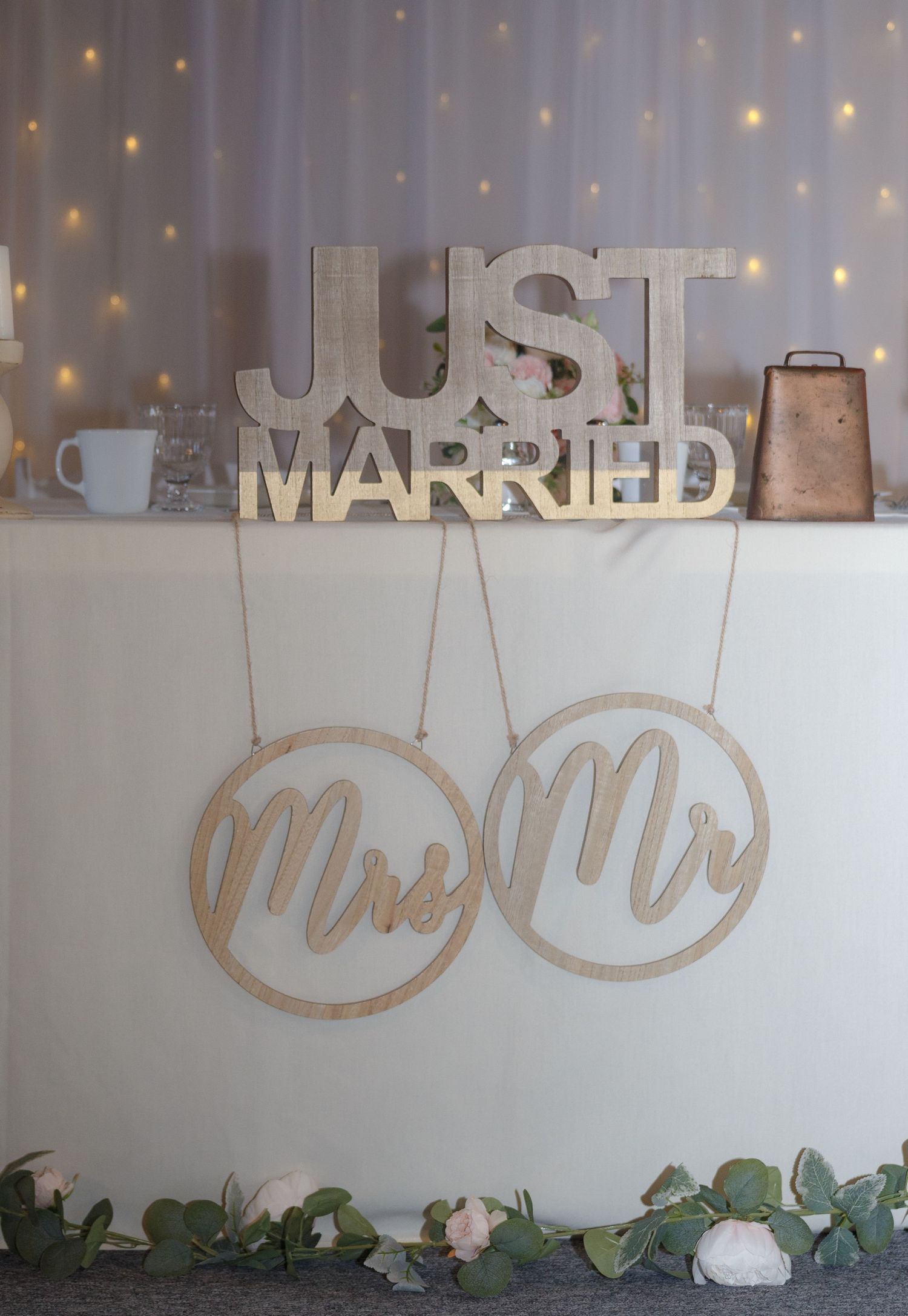 Just Married sign with decorative lettering displayed against a white wall with string lights.