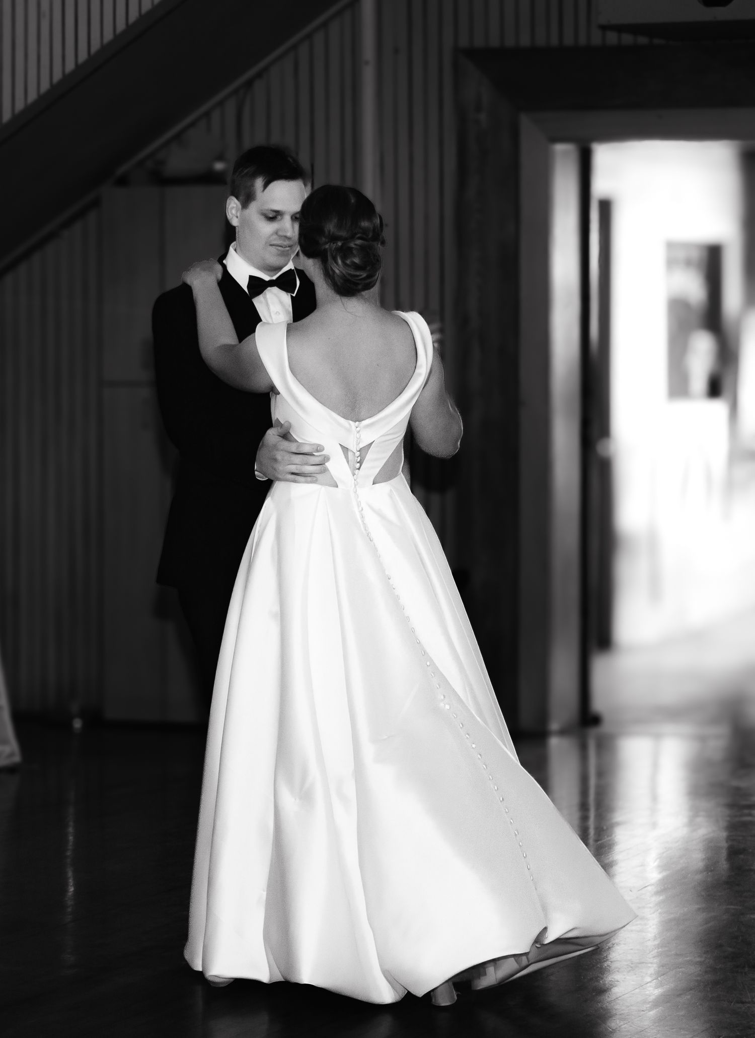 Dramatic black and white photo of a flowing wedding dress in a hallway.