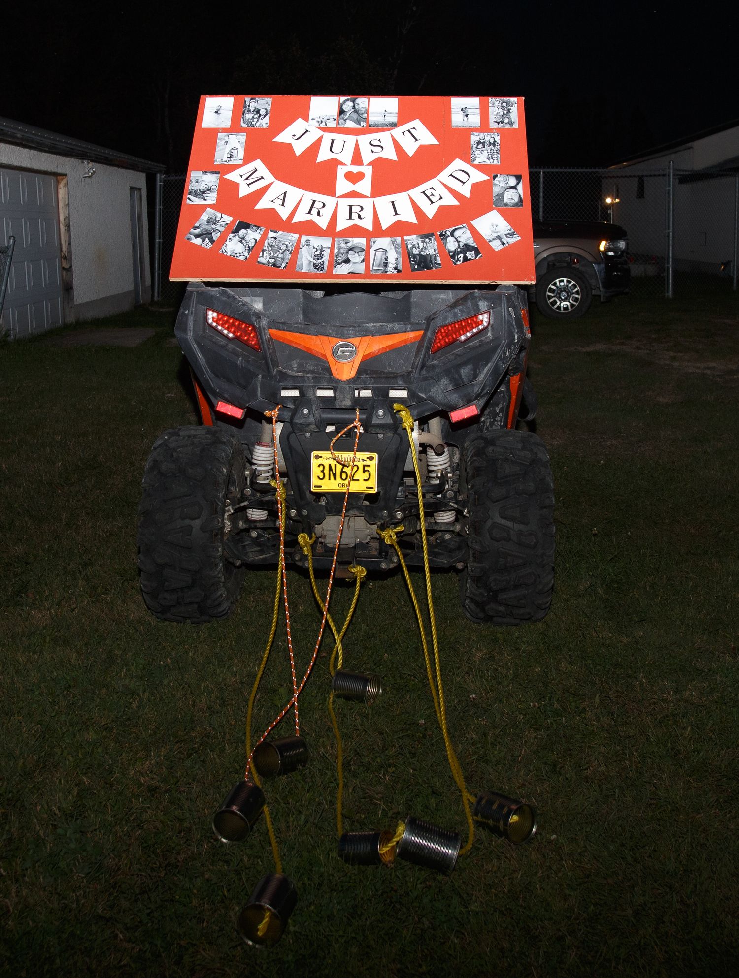 Decorated ATV with Just Married banner and lights parked on grass at night.
