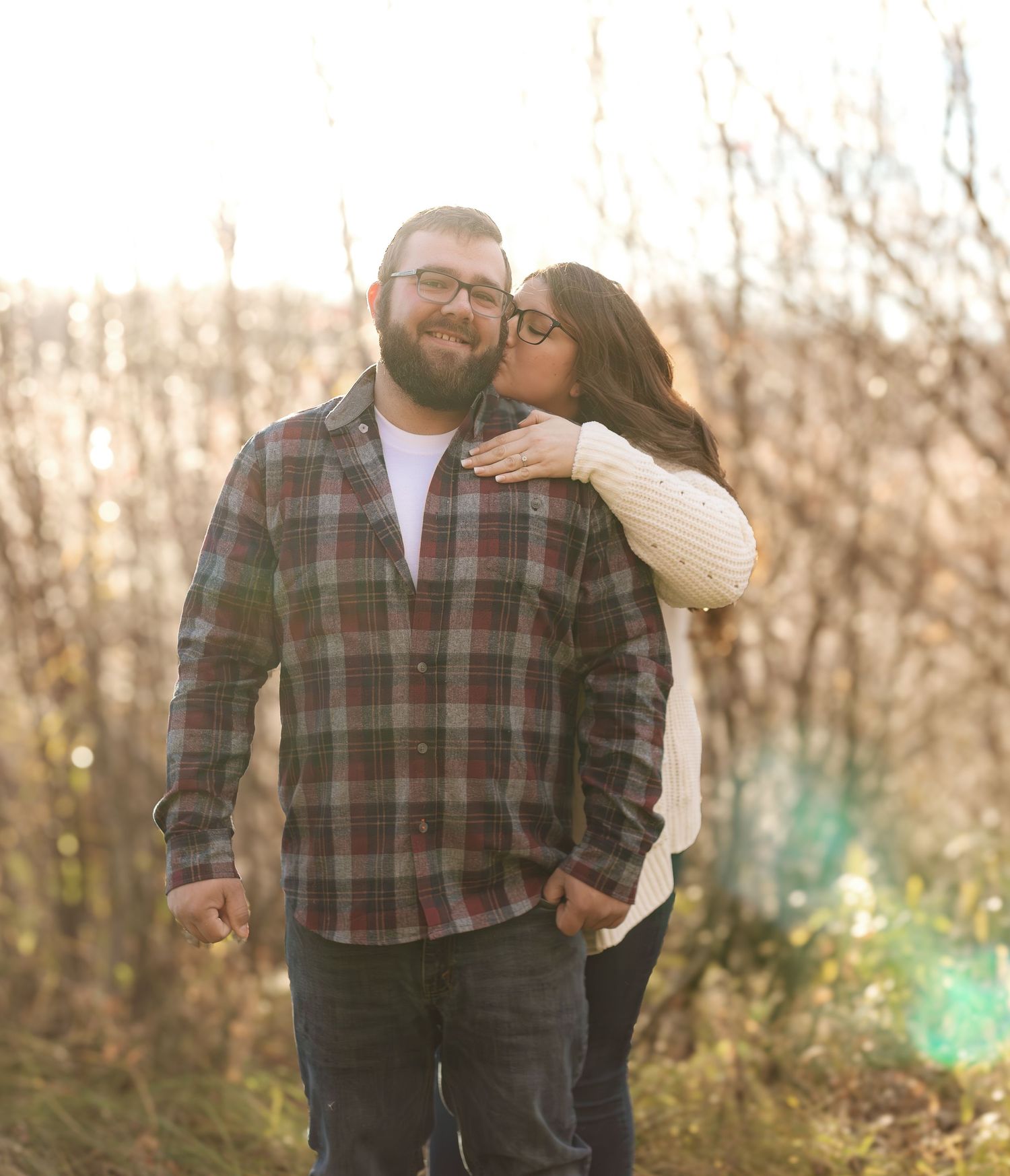 Couple in plaid sharing playful moments in autumn woodland setting.