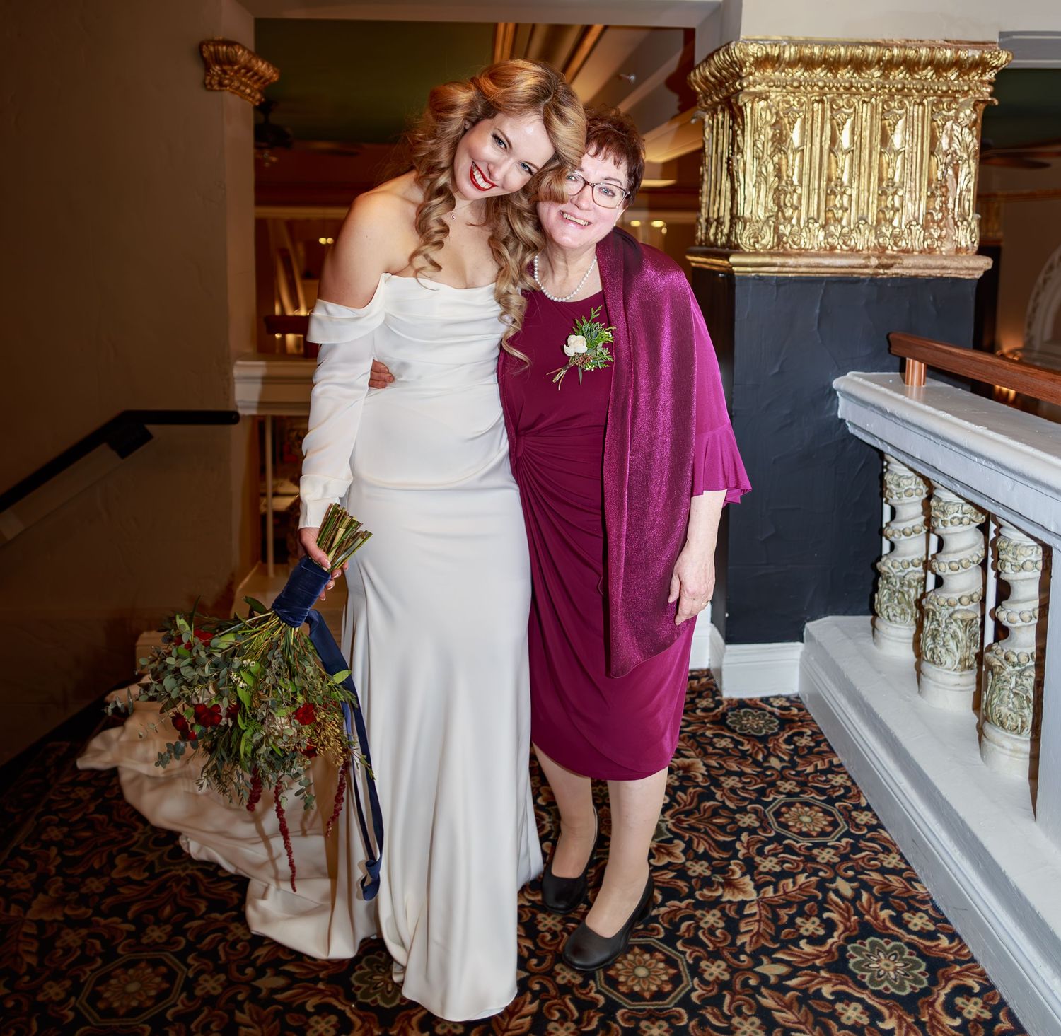 Wedding party members share candid moments in an elegant venue hallway.