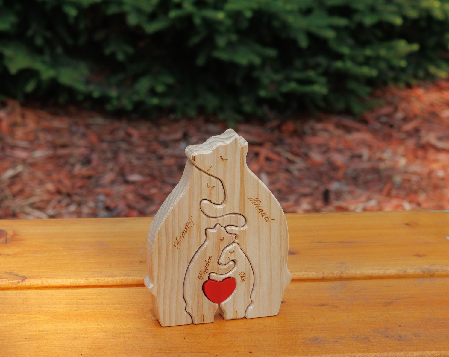 Wooden puzzle piece nativity scene decoration with heart detail sitting on outdoor wooden surface.