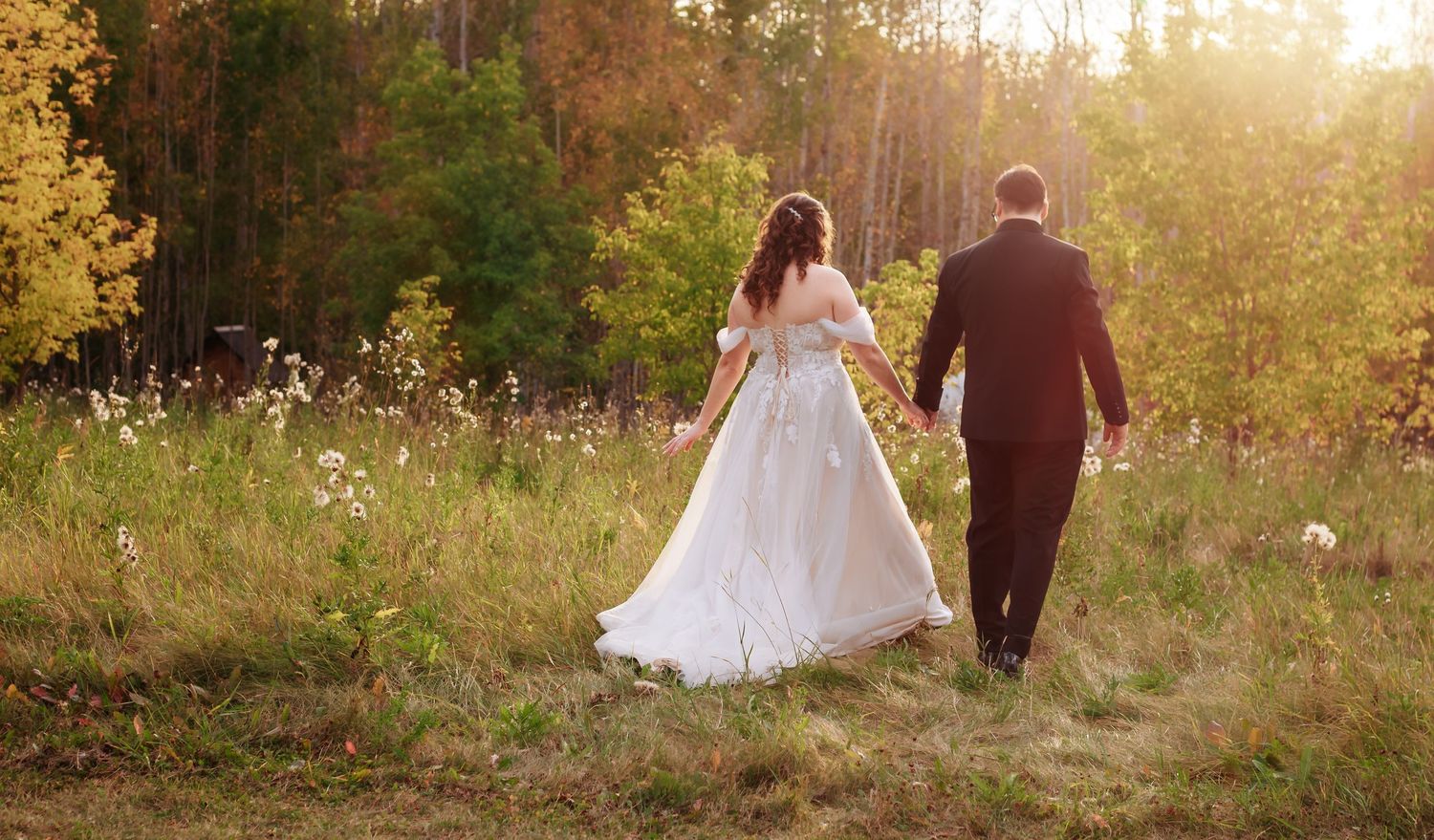 Golden hour wedding photography in a natural field with tall grass and trees.