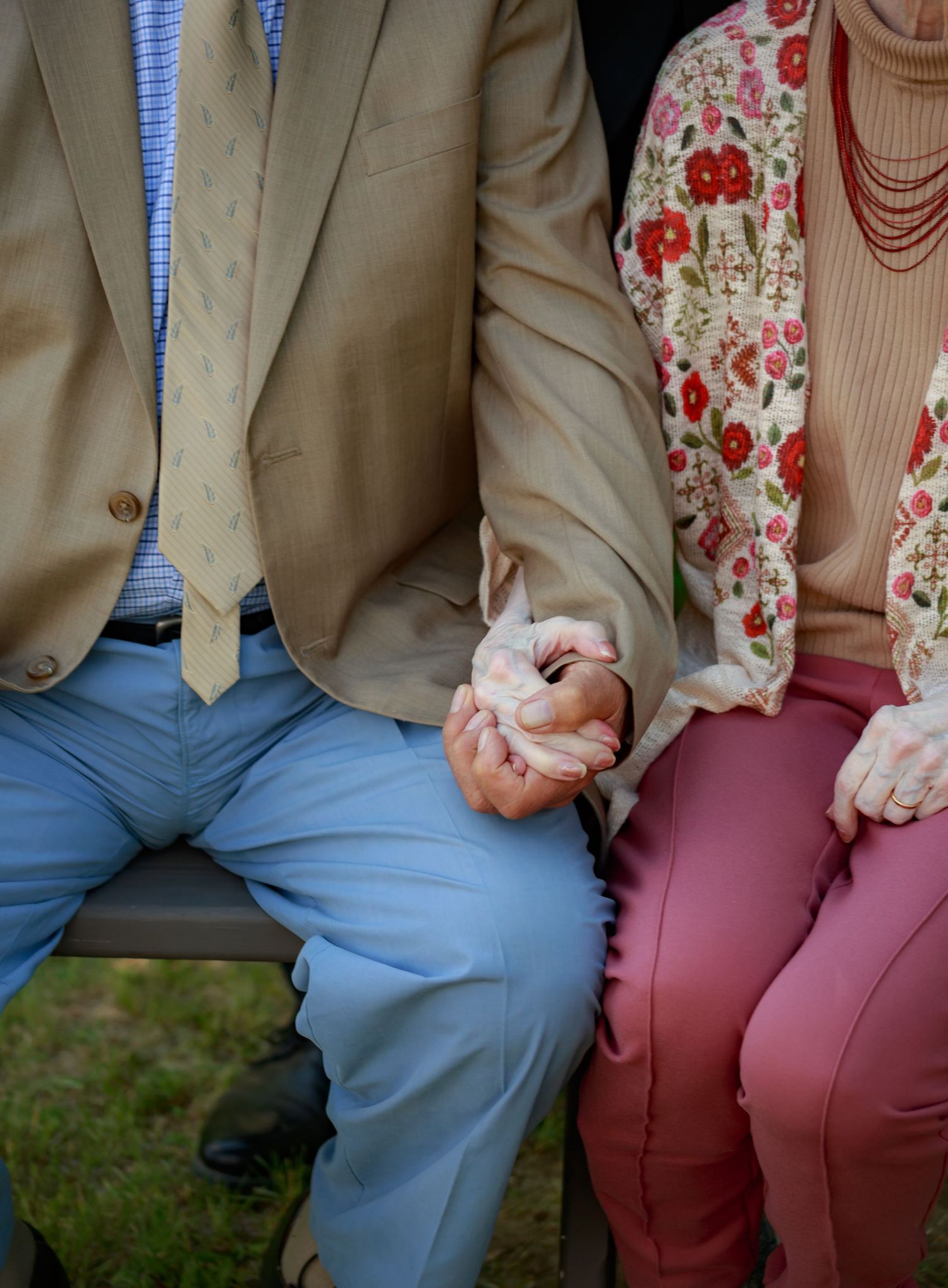 Close-up of two people sitting on bench showing contrasting blue and pink attire.
