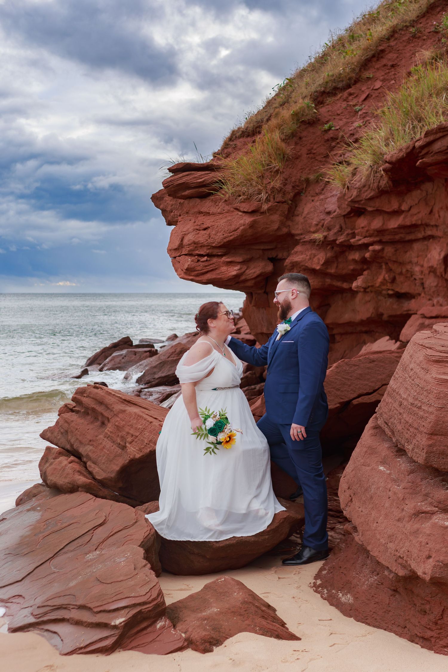 Coastal wedding ceremony taking place among dramatic red rock formations by the ocean.