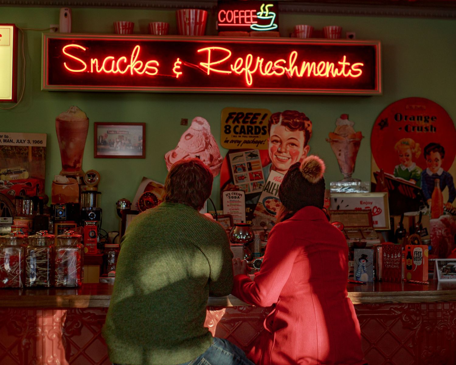 A retro-style snack bar interior with neon signage and red lighting.