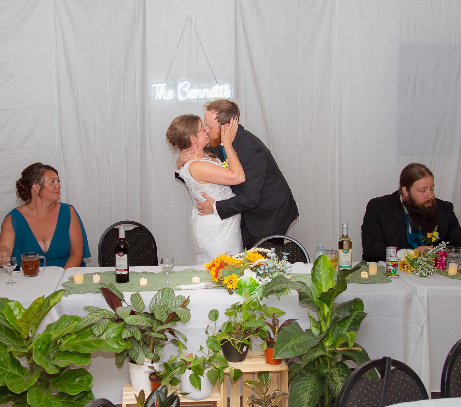 Wedding reception table decorated with tropical plants and colorful floral arrangements.