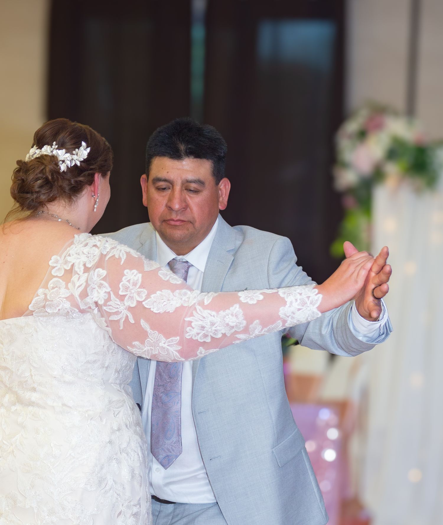 Elegant dance moves during a wedding reception with white decor and twinkling lights.