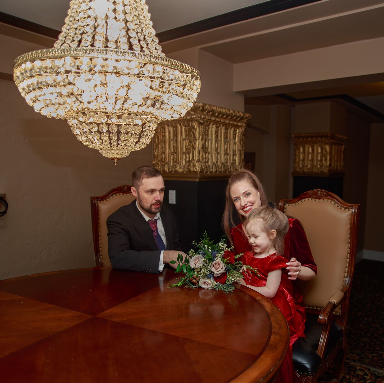 Wedding party gathered under crystal chandeliers in an elegant reception room.