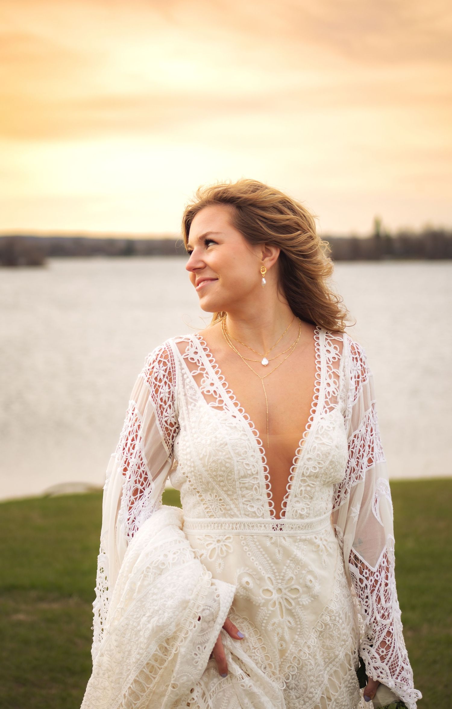 A lace wedding dress with bell sleeves captured during golden hour by a lake.