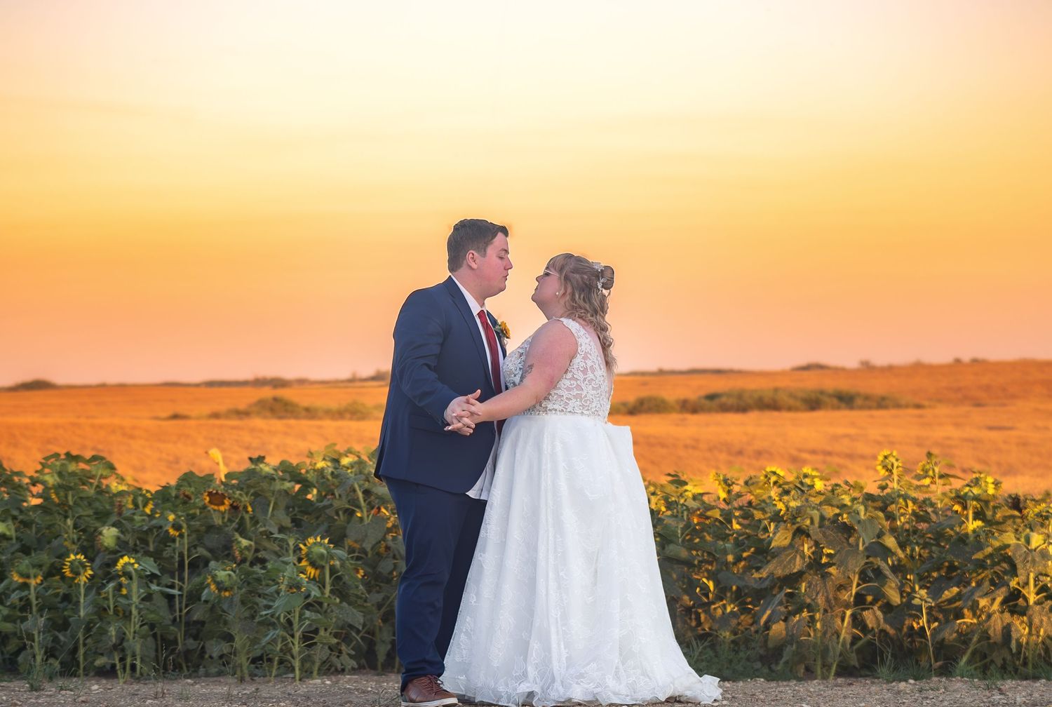 Couple shares romantic moment in sunflower field during golden sunset.