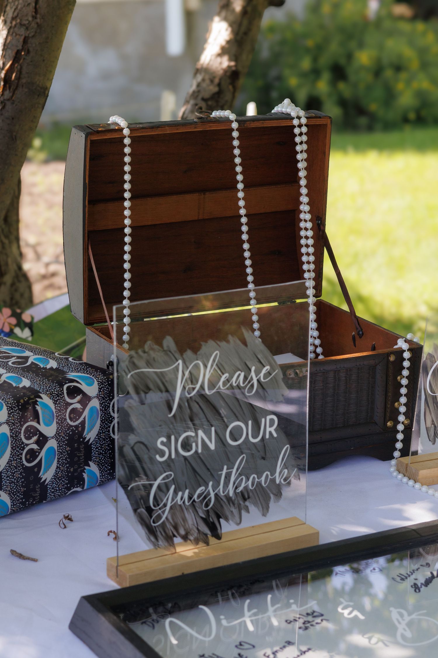 An elegant wedding guest book display with hanging crystal decorations and chalkboard signage.