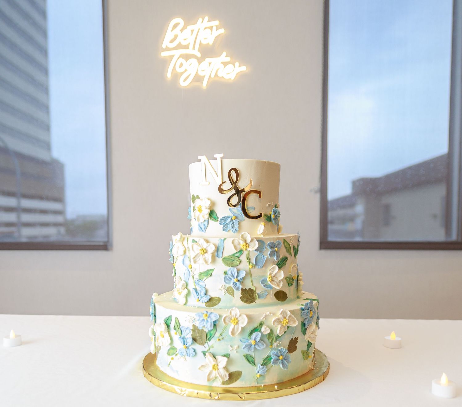 Three-tiered wedding cake decorated with light blue and gold floral designs.