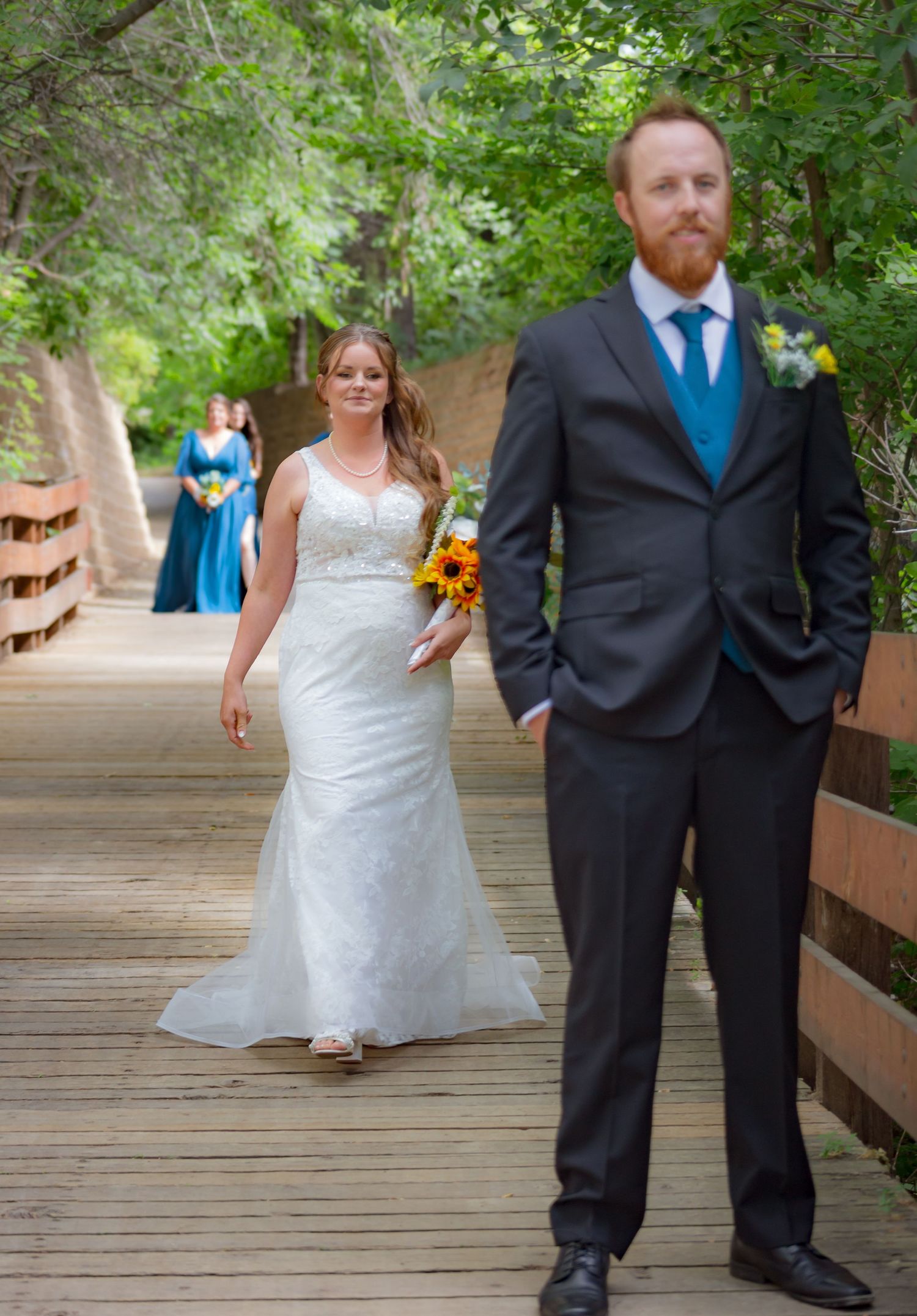 Wedding couple walks along a wooden boardwalk surrounded by lush greenery.