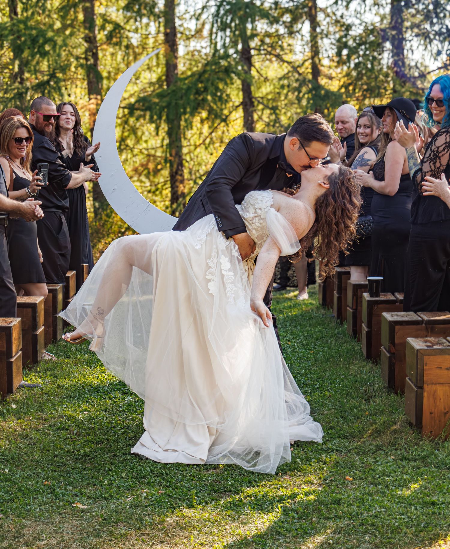 Wedding ceremony guests seated on rustic wooden benches in a garden setting.