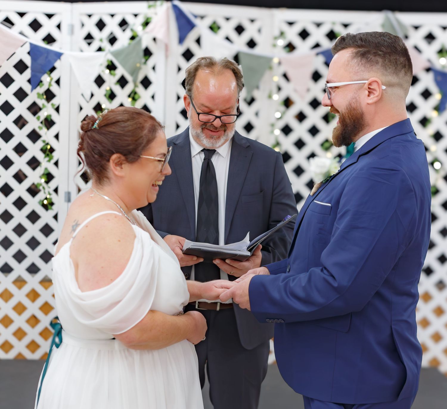 Wedding ceremony taking place in front of a white lattice backdrop.