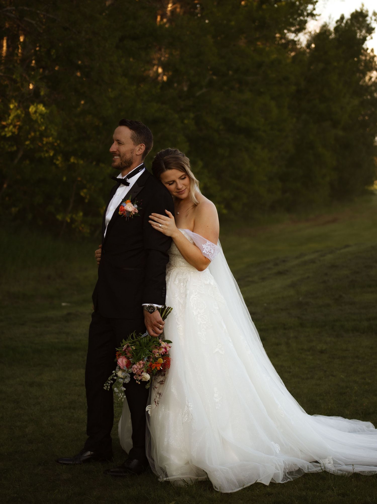 A romantic wedding moment captured outdoors with natural greenery in the background.